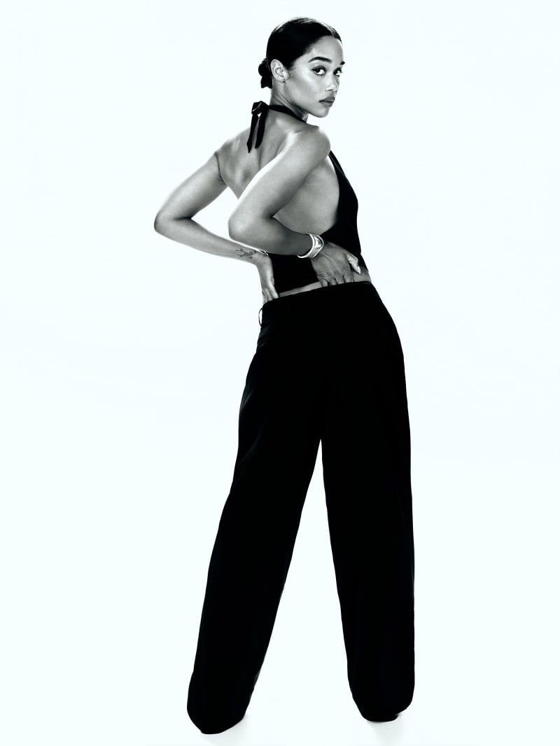 A woman wearing black Petites Danielle Oversized Pant, high-waisted with pleats, wide legs, and a fitted waistband.