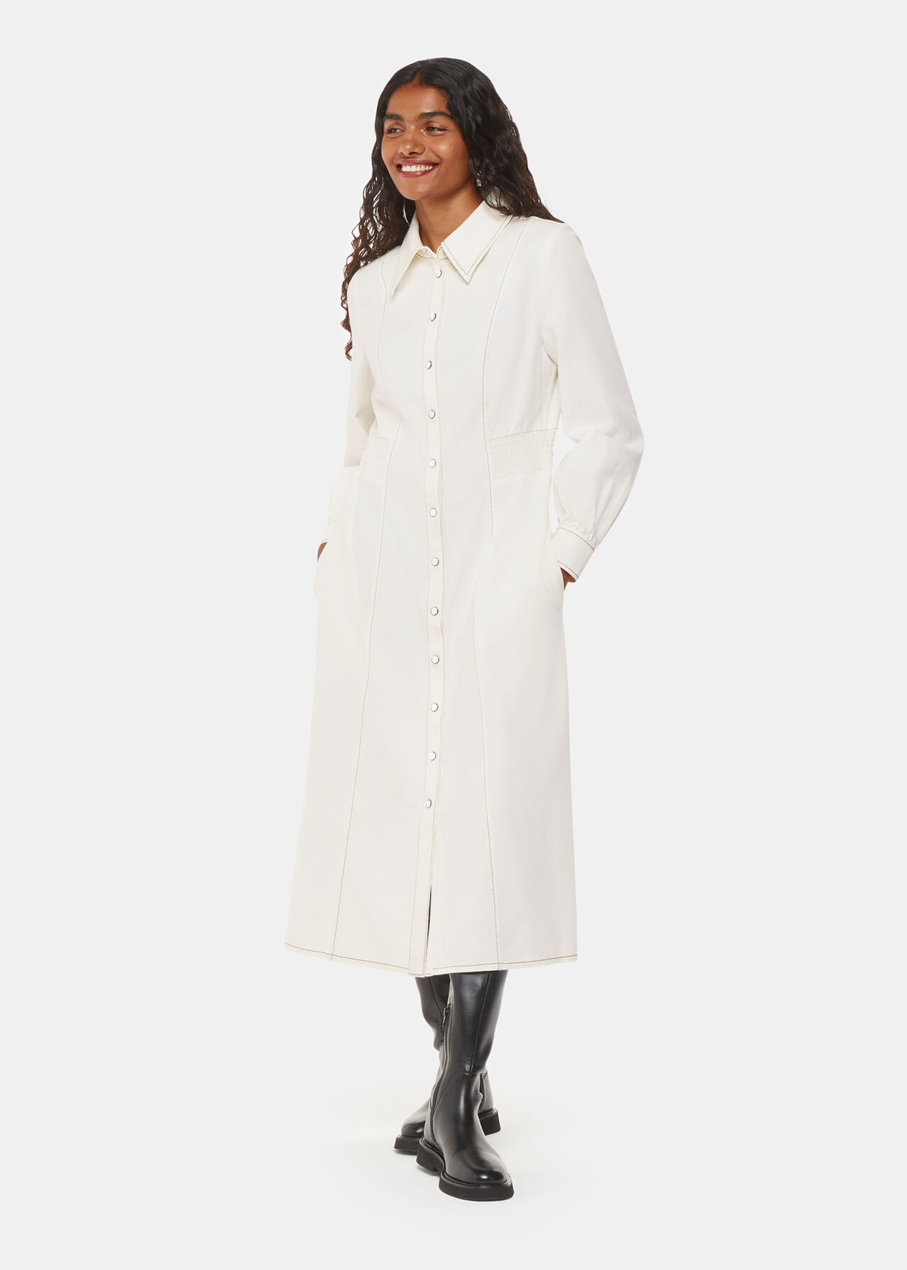 A woman wearing a white denim midi dress with a collared neck, front buttons, and long sleeves.
