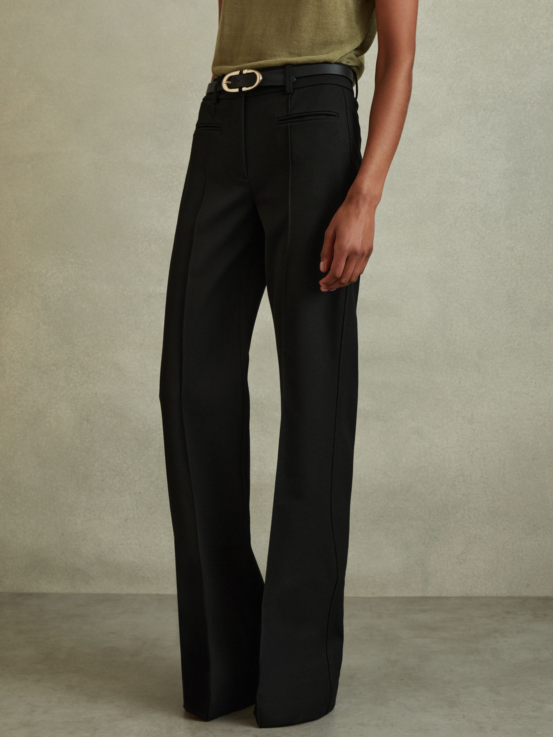 A pair of black high-rise flared trousers with a tailored fit, featuring pinched front seams and jetted front pockets.
