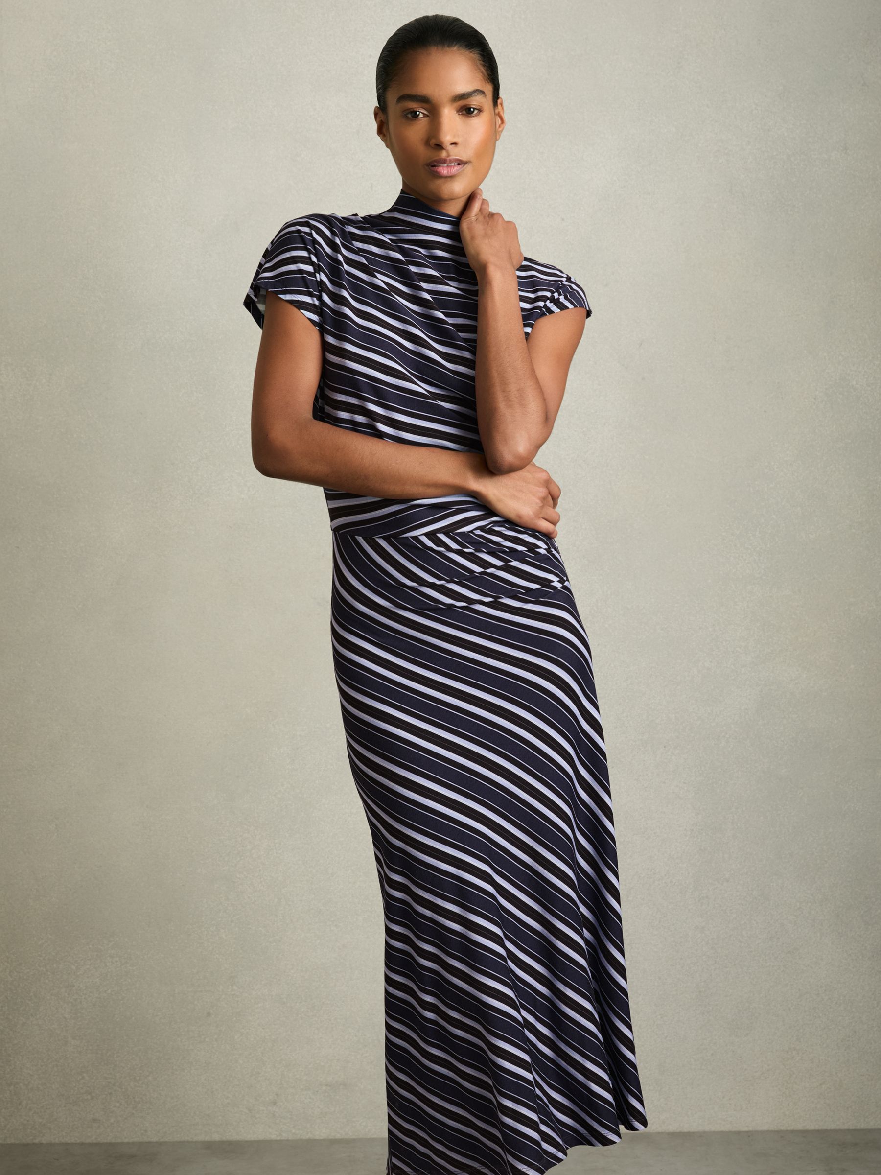 A woman wearing a blue stripe-print midi dress with draping and a high neckline.