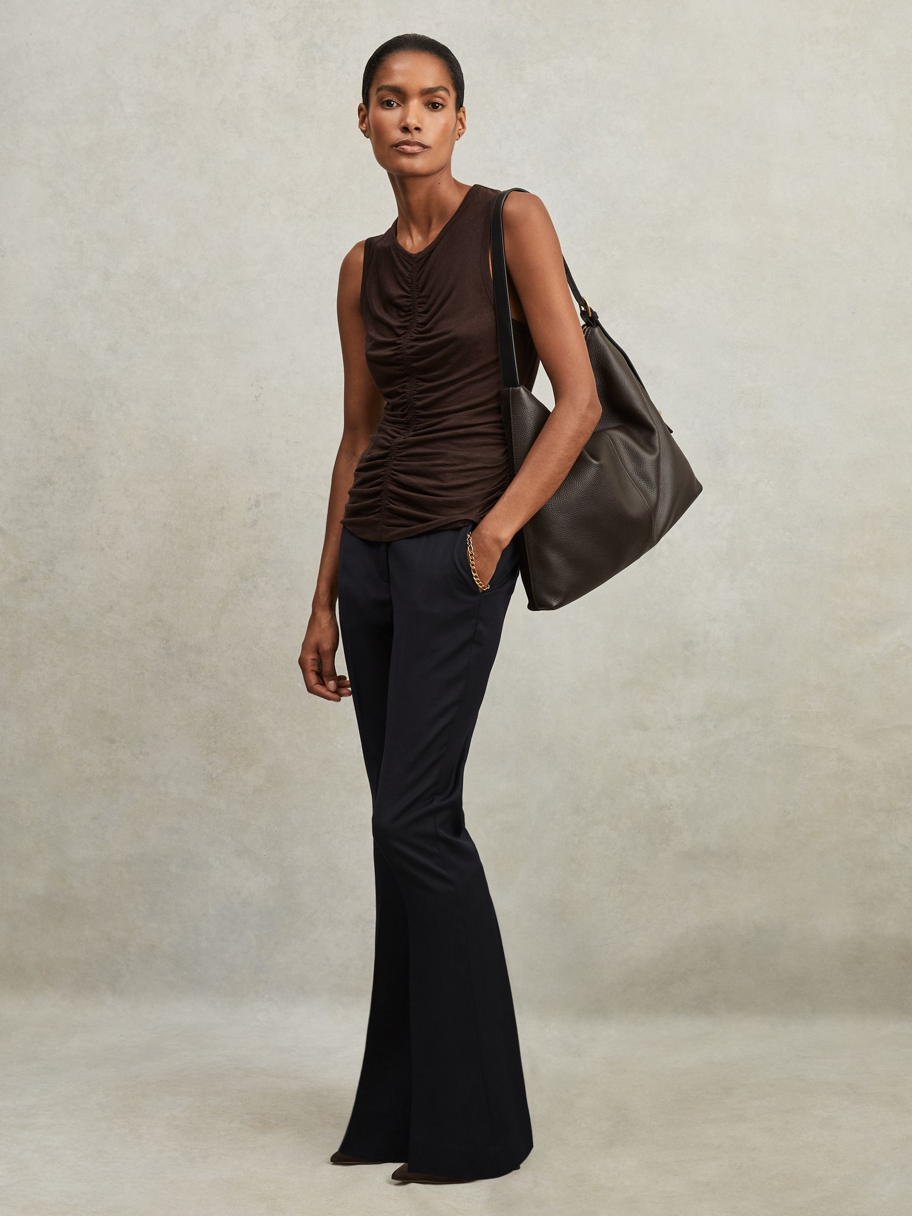 A pair of navy petite wool-blend tailored flared suit trousers with a mid-rise waist, belt loops, and pressed creases, shown on a female model.