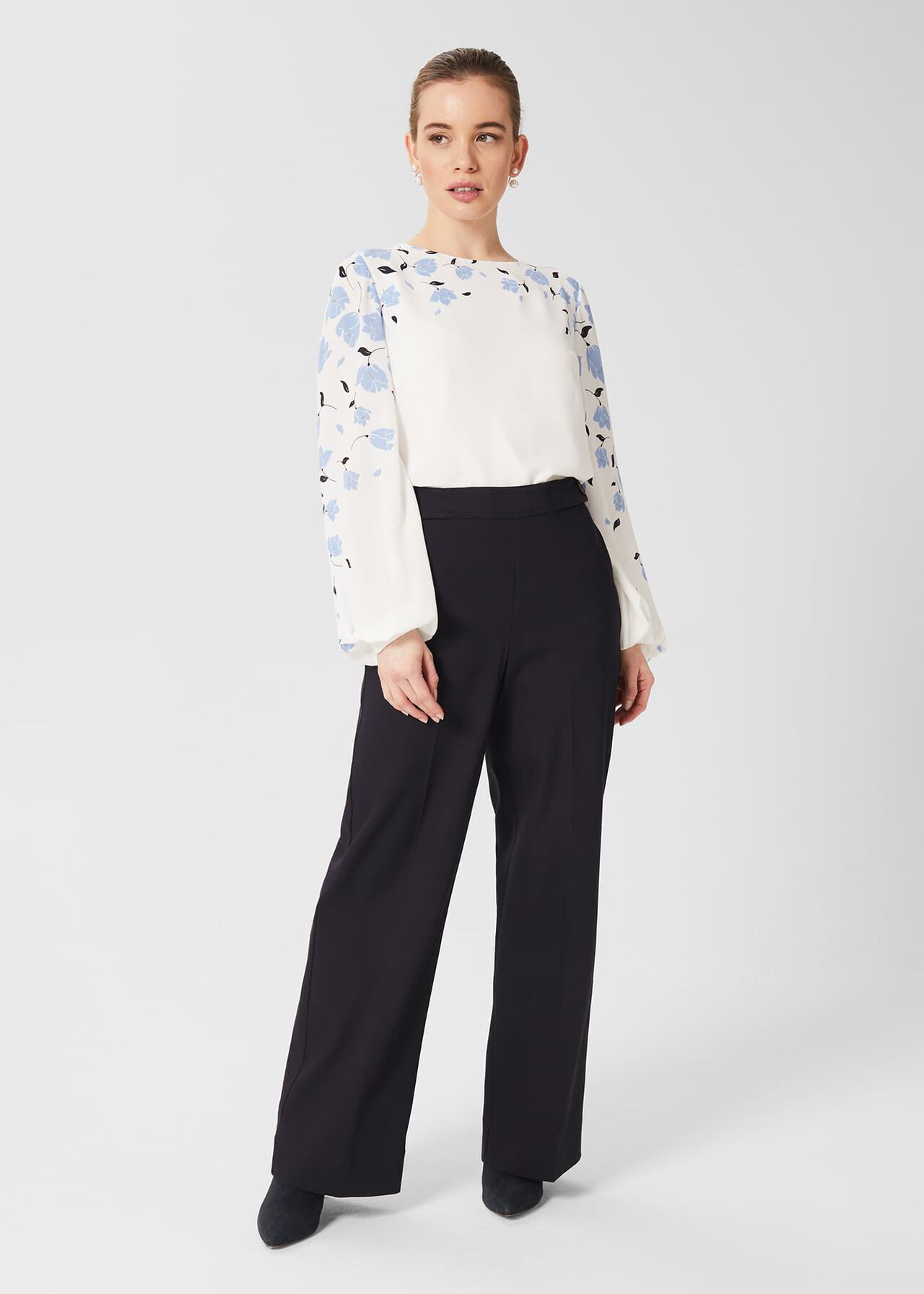 A pair of black women's trousers with a straight-leg cut, high waist, and button fastening, worn by a female model.