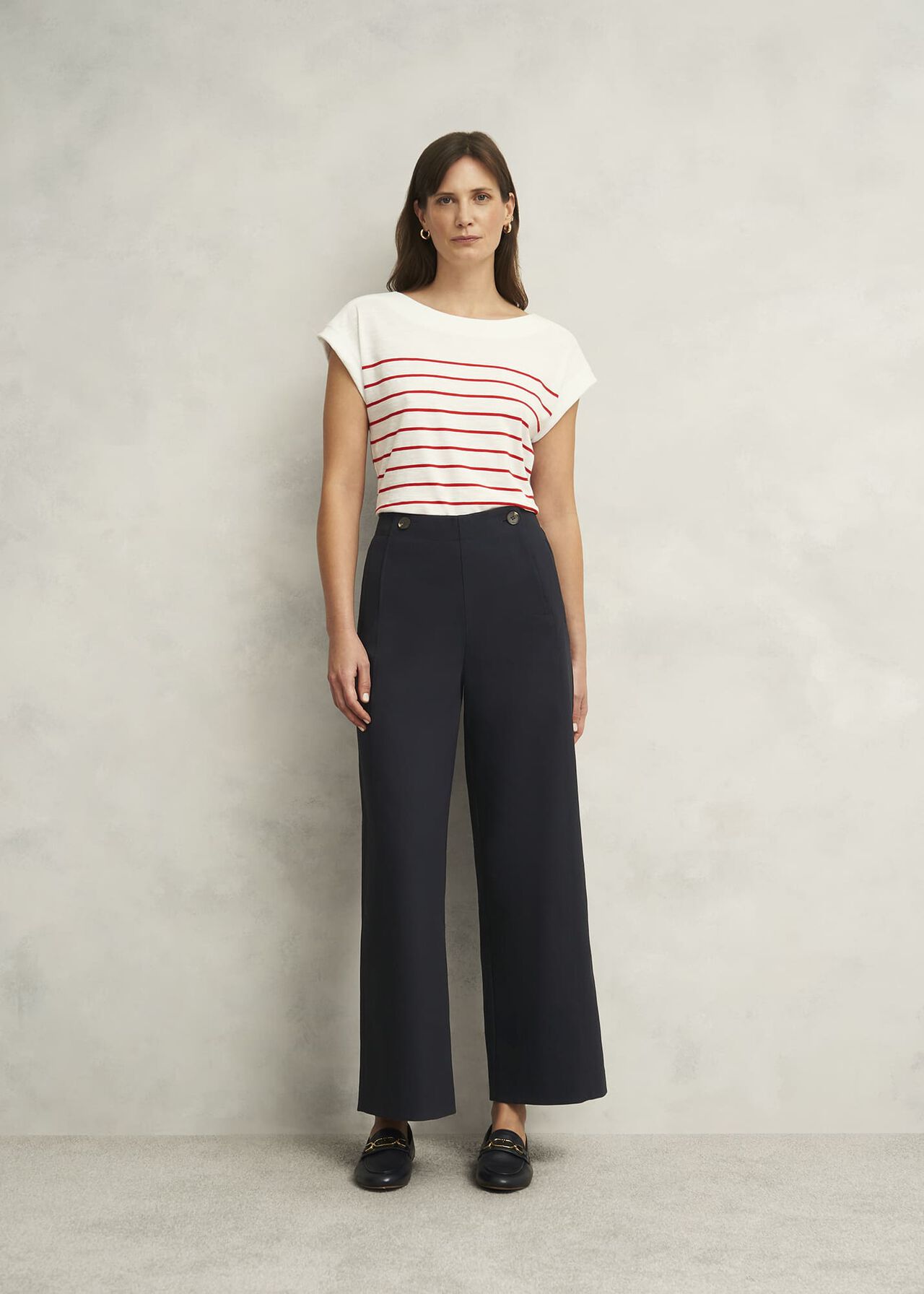 A woman wearing black high-waisted wide-leg trousers with side button details, paired with a white and red striped top.