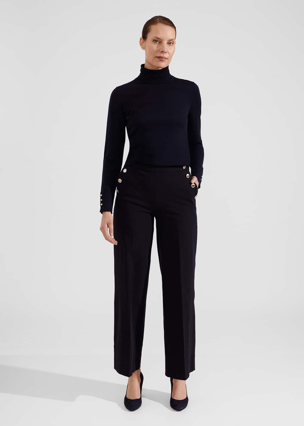A pair of black wide-leg trousers with a high waist, hook and bar fastening, and a model wearing them.