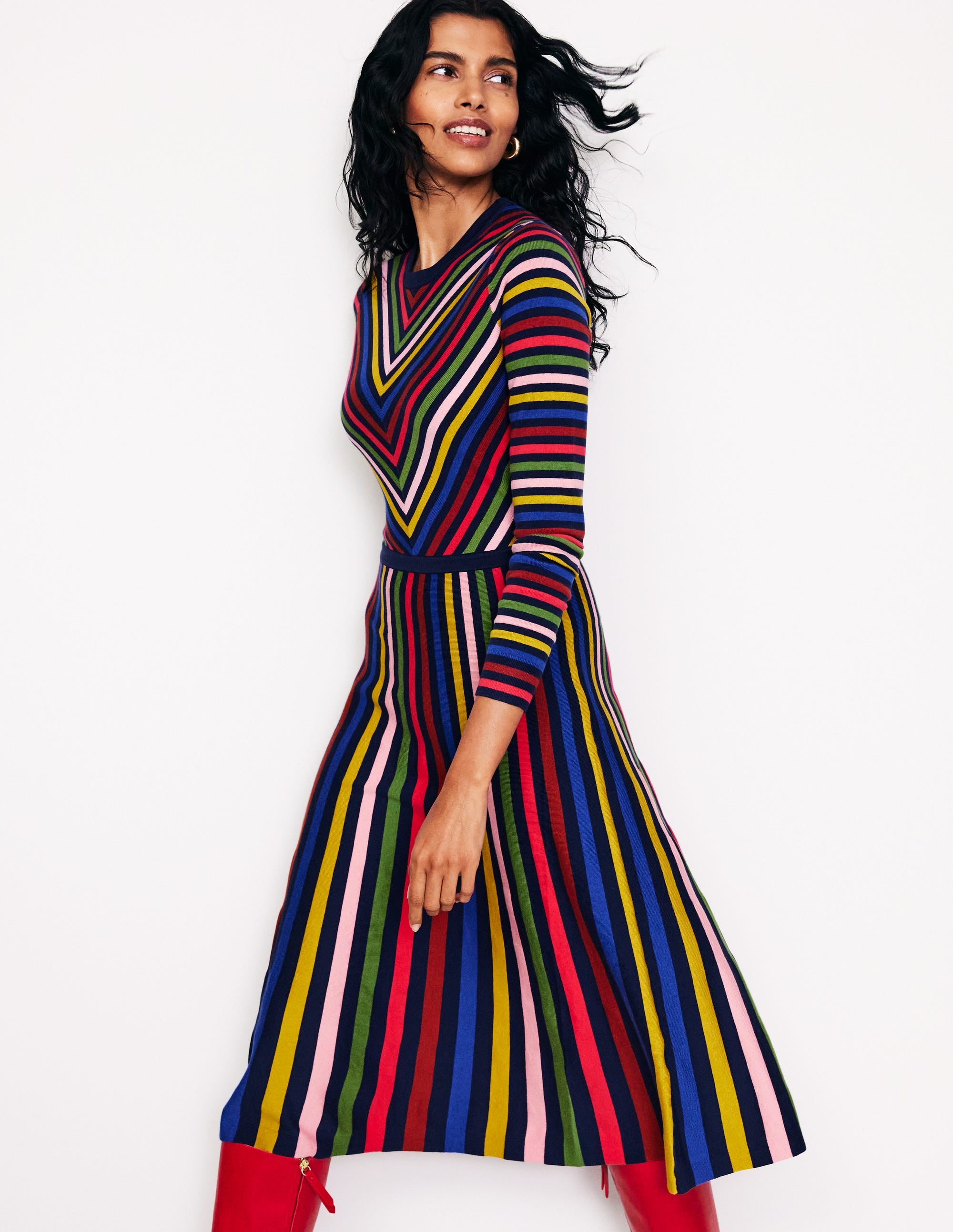 A woman wearing a multicolour striped midi dress with long sleeves and a fit-and-flare silhouette.