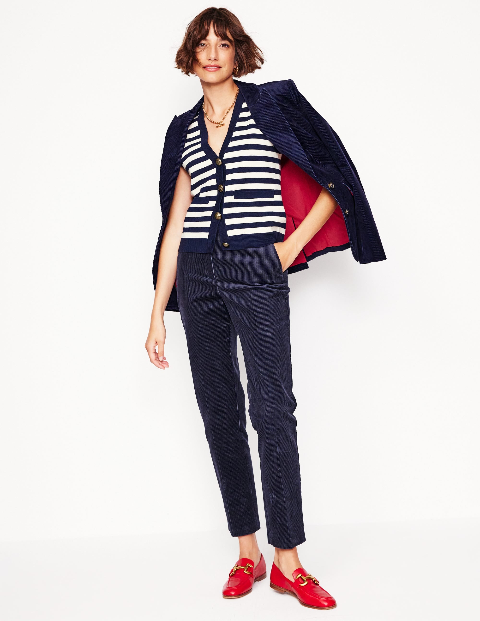 A pair of navy corduroy trousers with a tailored fit, sitting on the natural waist, with pockets and a concealed fastening.