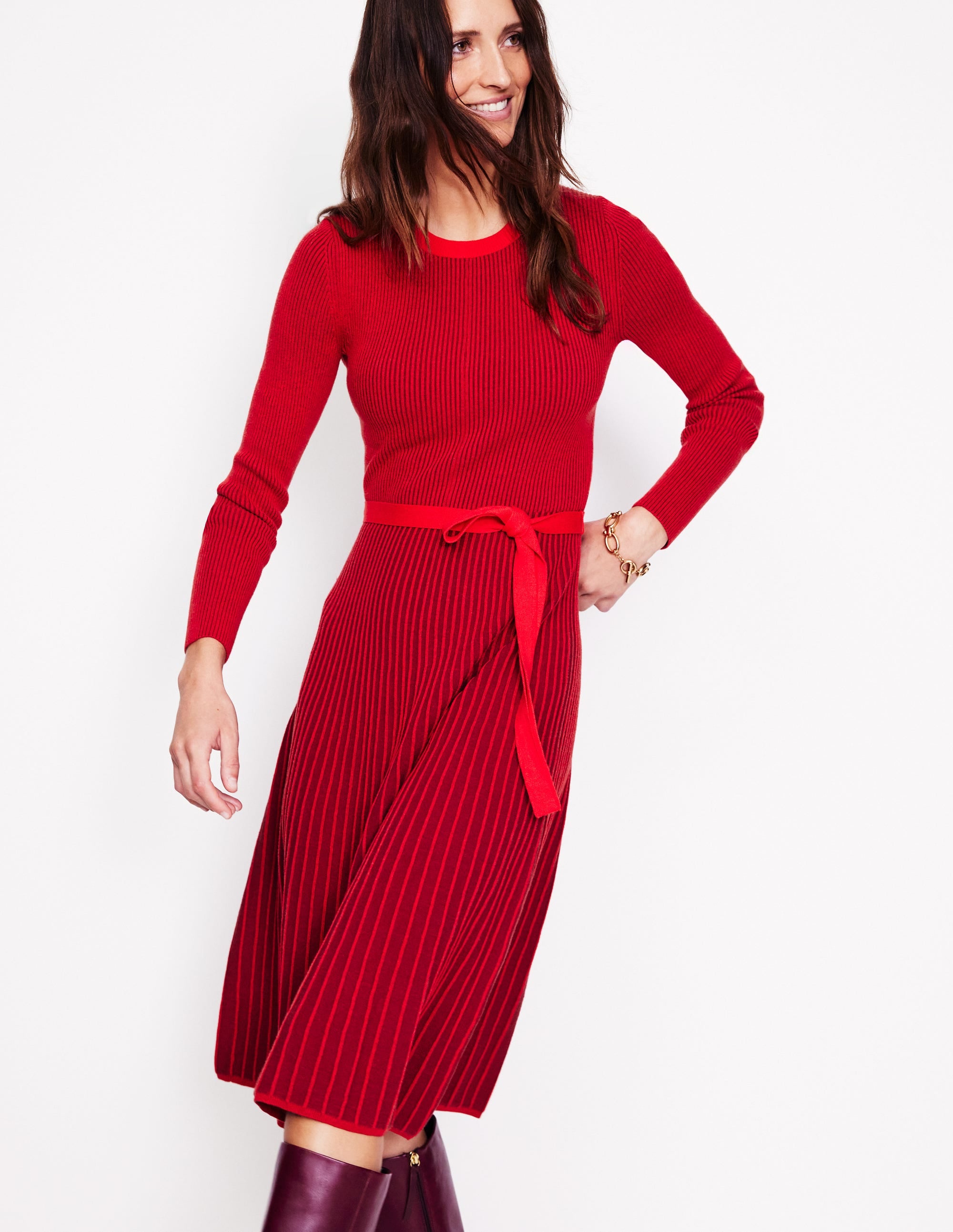 A woman wearing a red knitted midi dress with short sleeves, a round neckline, and a flared skirt, standing against a plain background.
