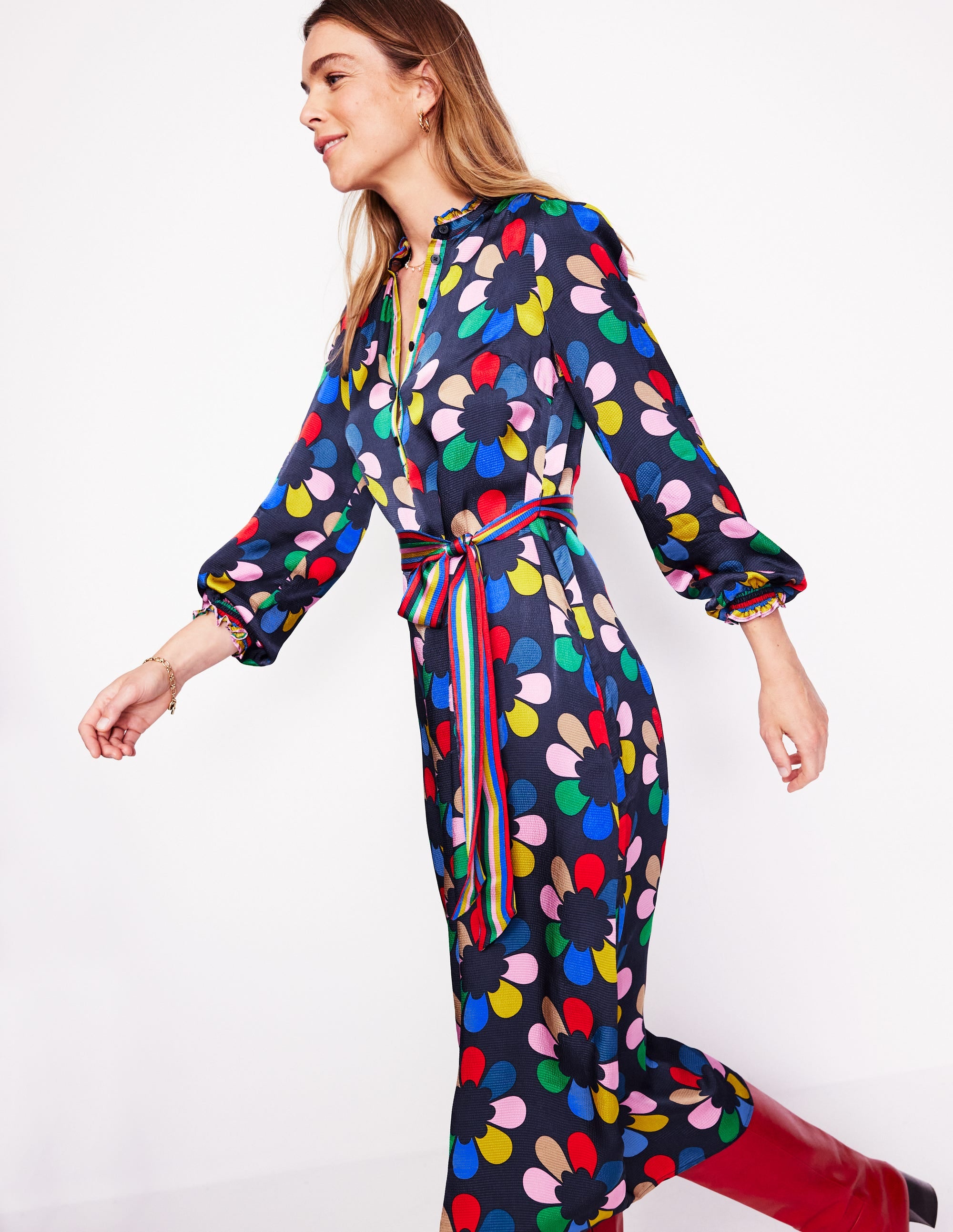 A woman wearing a multicolour floral satin midi dress with smocking, frill details, and a self-fabric belt.