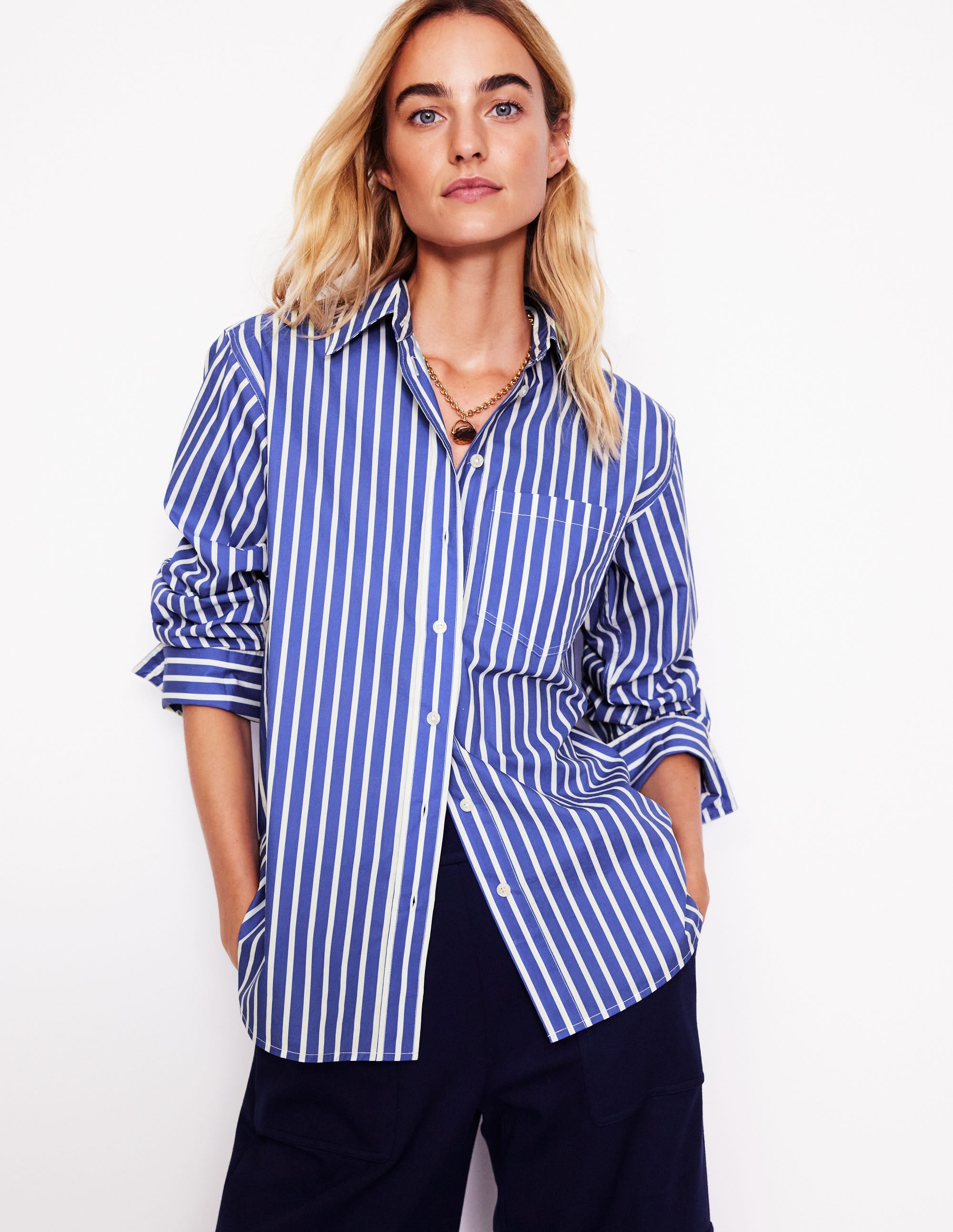 A woman wearing a blue and ivory striped cotton shirt with a classic collar and button-down front.
