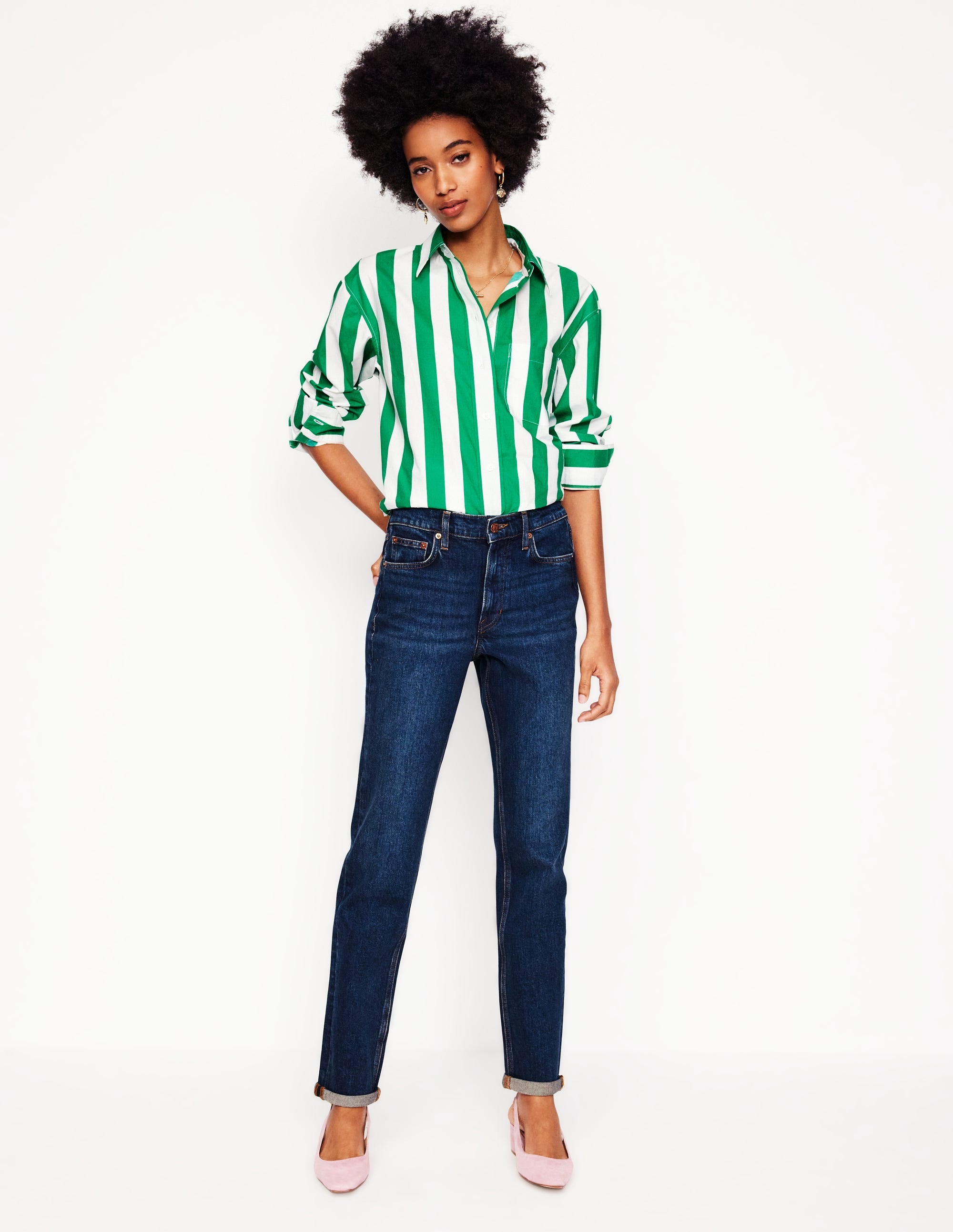A woman wearing dark vintage wash girlfriend jeans with rolled-up hems, paired with a green and white striped shirt.