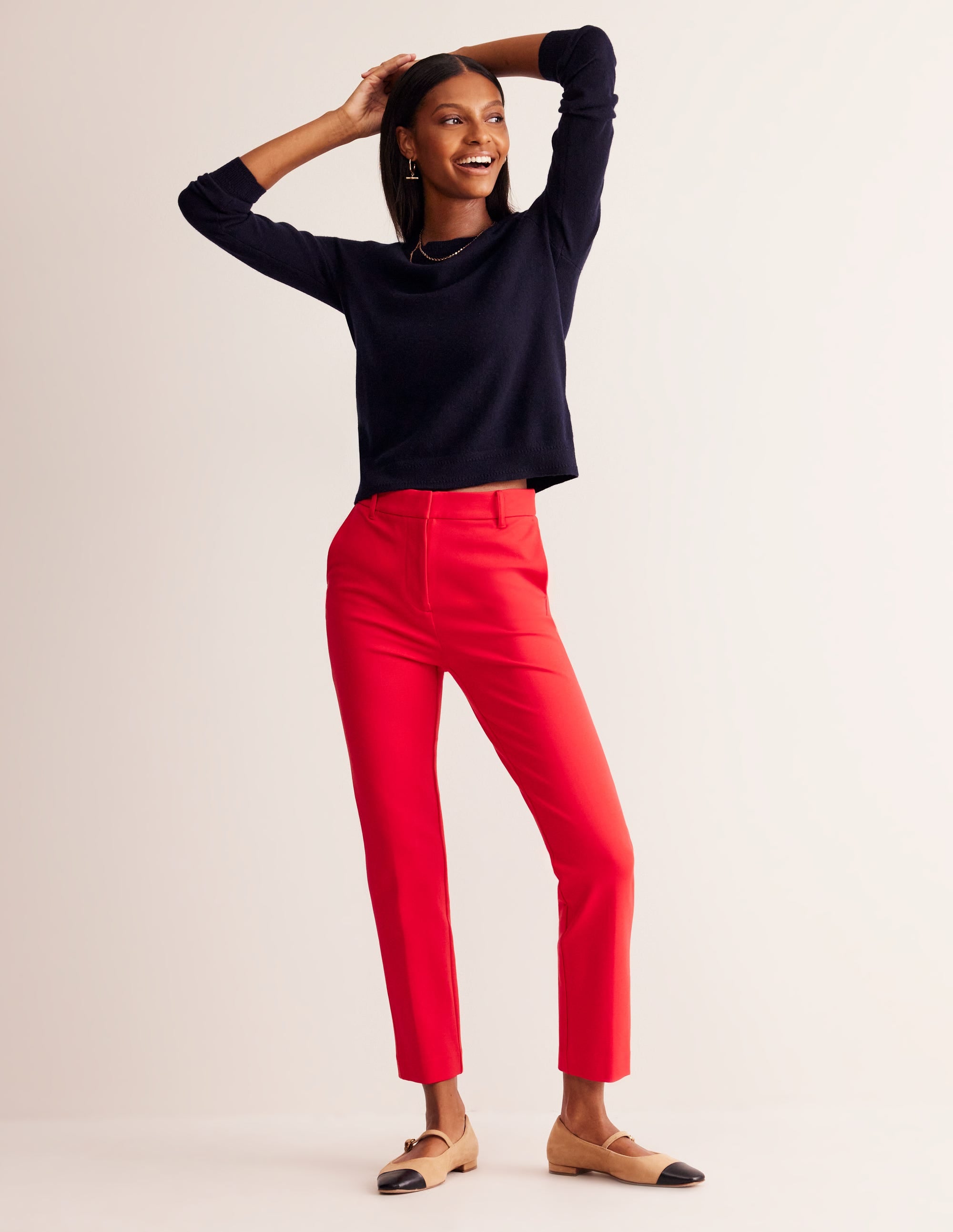 A pair of red women's trousers with a slim fit and ankle-length, featuring a concealed front fastening.
