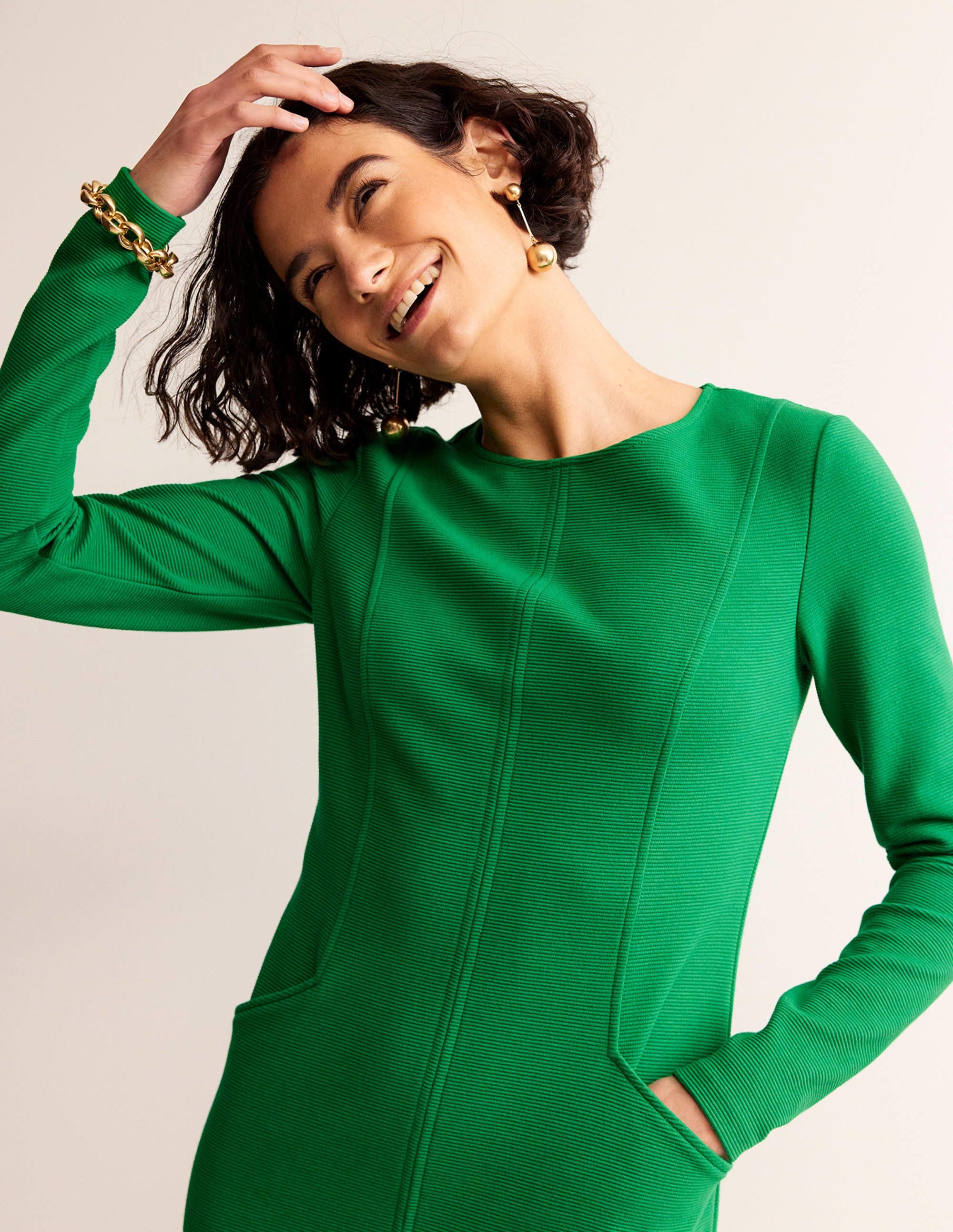 A woman wearing a green Ottoman fabric dress with a shift silhouette and three-quarter sleeves.