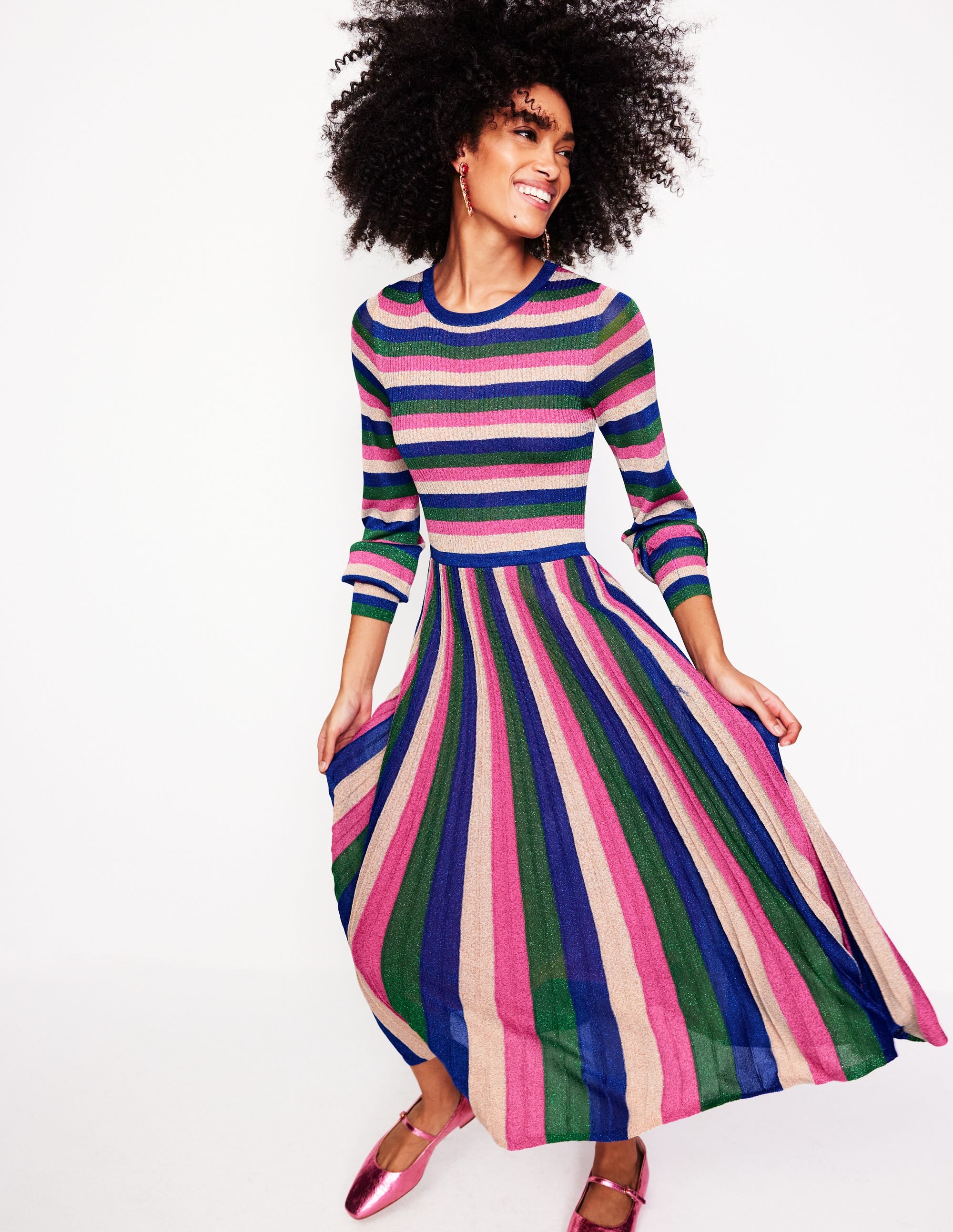 A woman wearing a ribbed metallic dress with pink, green, and gold stripes, long sleeves, and a midi length.