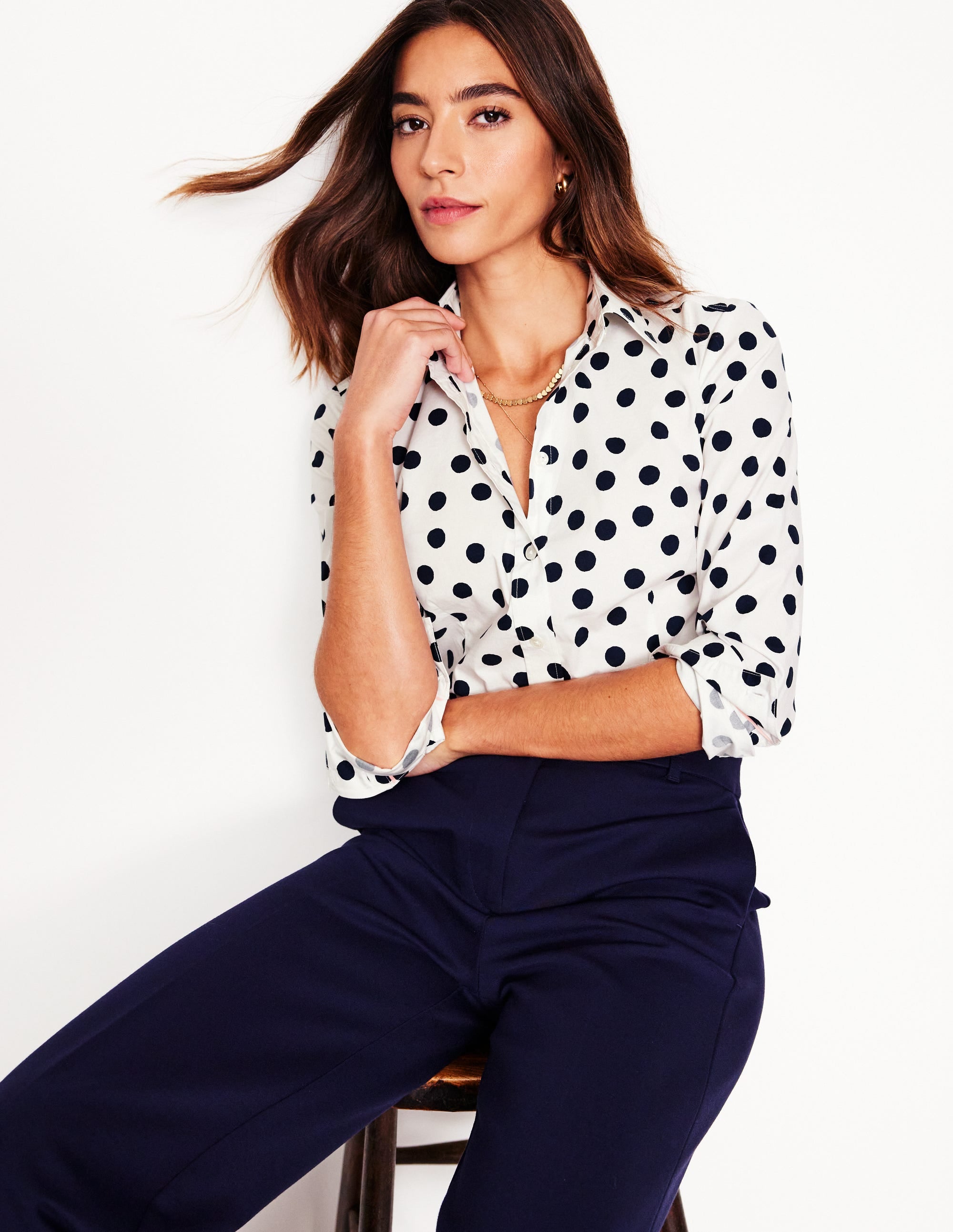 A woman wearing a white shirt with navy abstract dots, a collar, and three-quarter length sleeves.