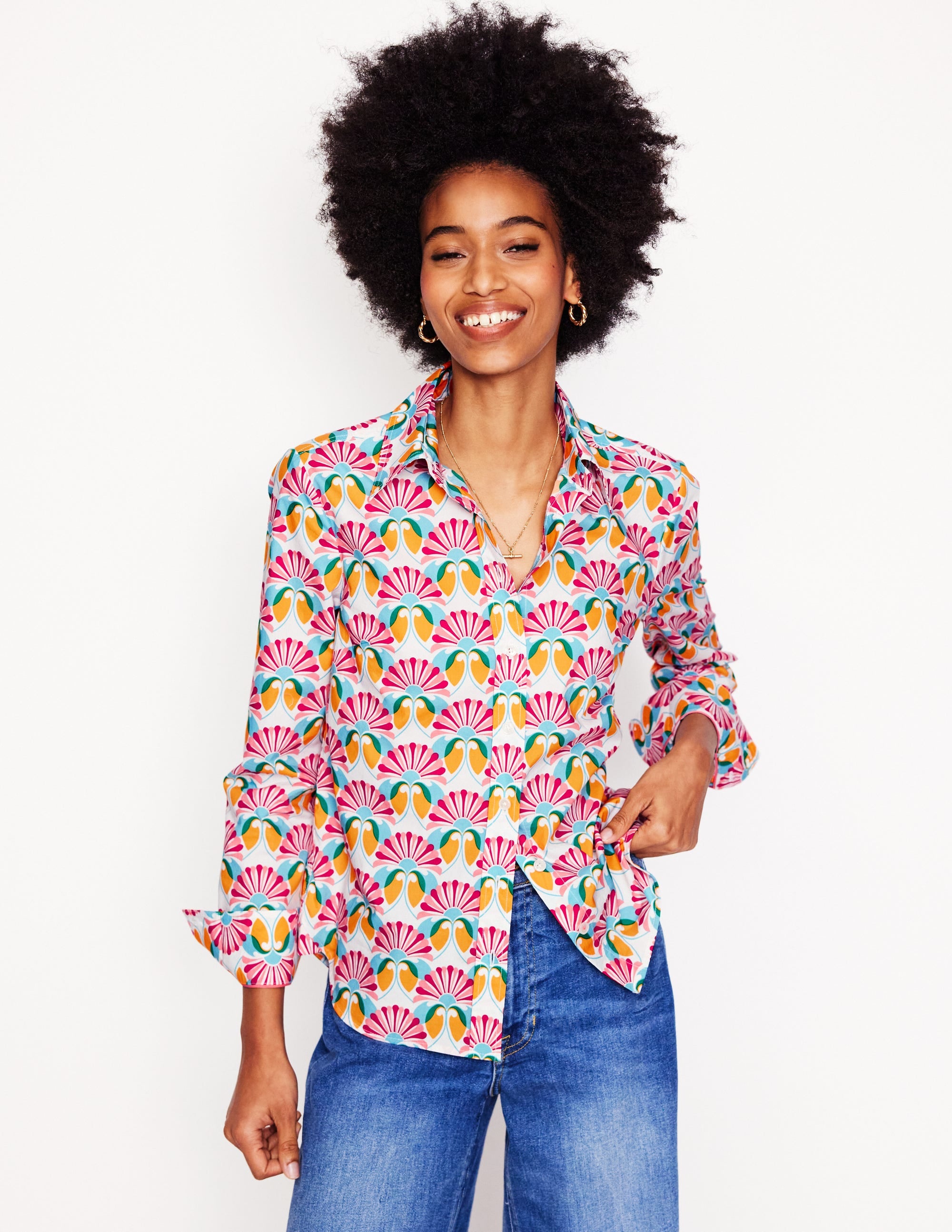 A woman wearing an ivory cotton shirt with a vibrant Daisy Bloom Geo pattern, long sleeves, and a curved hem.