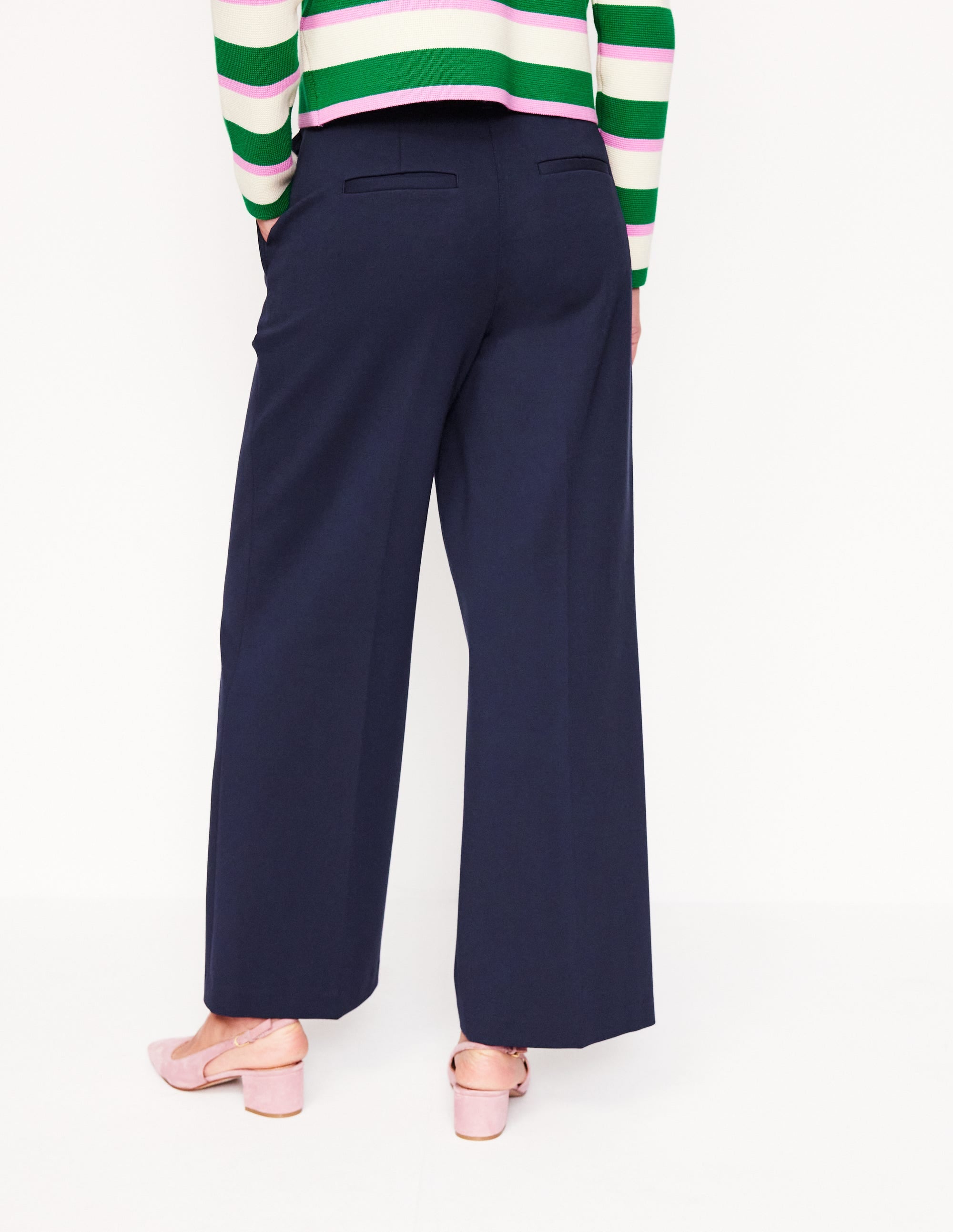 A woman wearing navy cropped ponte trousers with a straight fit, paired with a striped top, and pink heels.