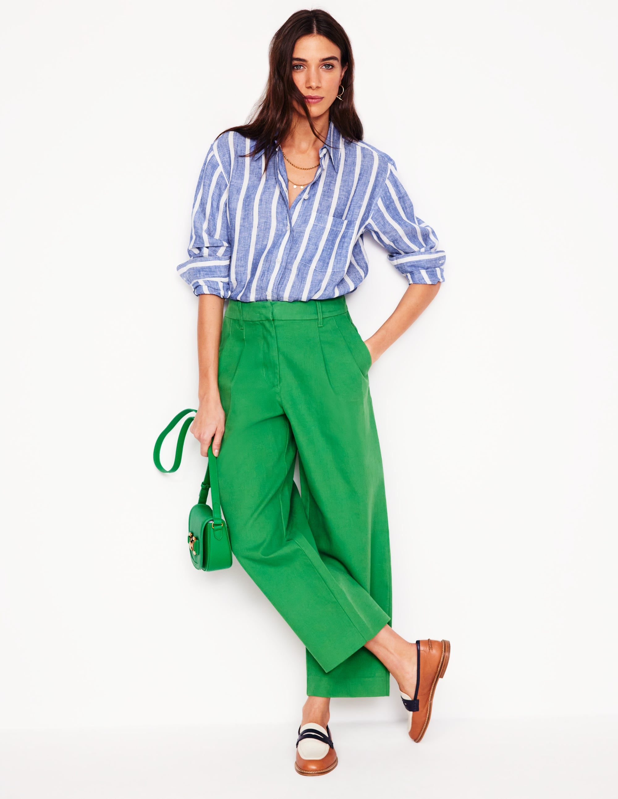 A woman wearing a bright blue linen shirt with a woven Breton pattern, long sleeves rolled up, and a collar.