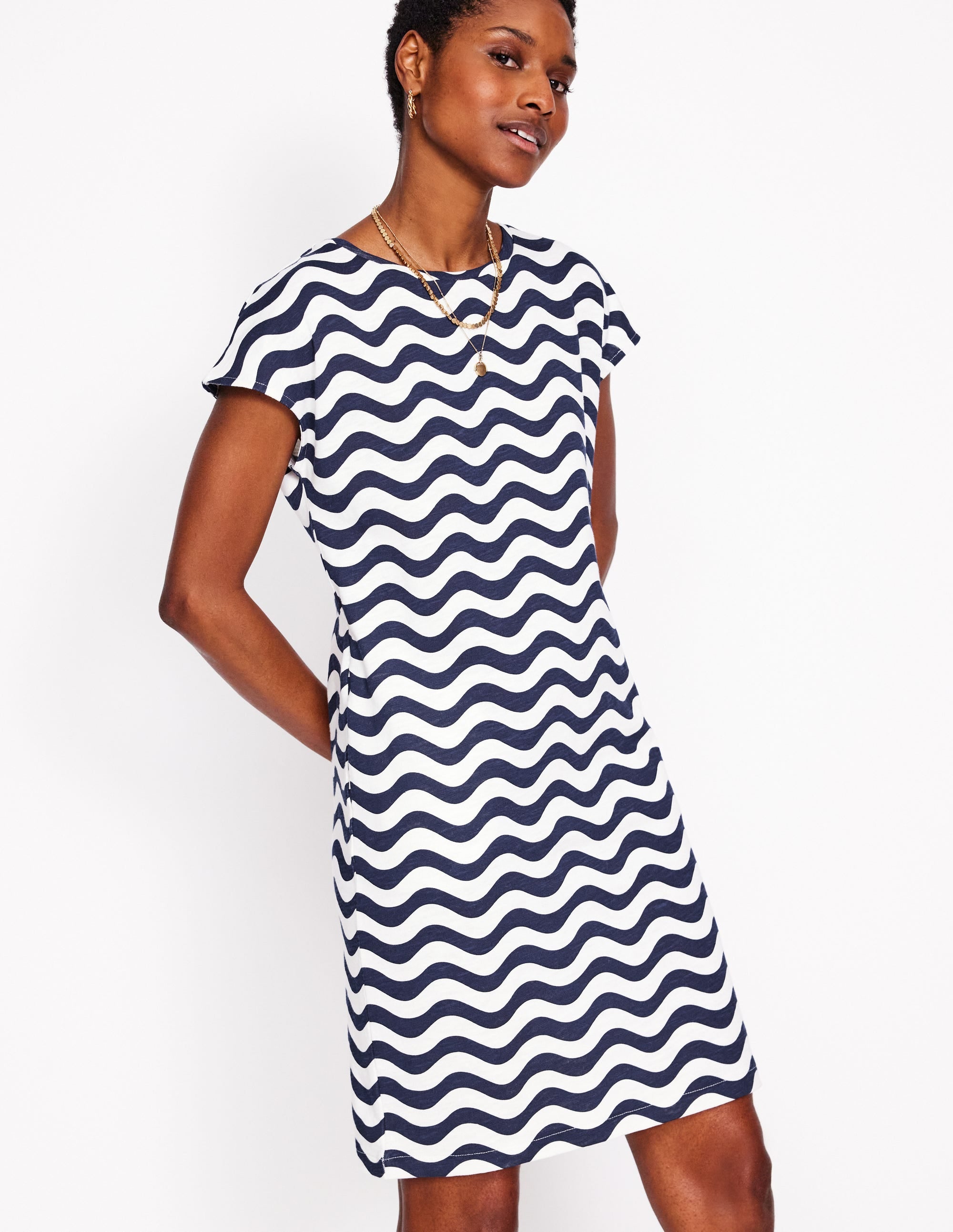 A woman wearing a navy blue and white patterned T-shirt dress with short sleeves, standing against a white background.