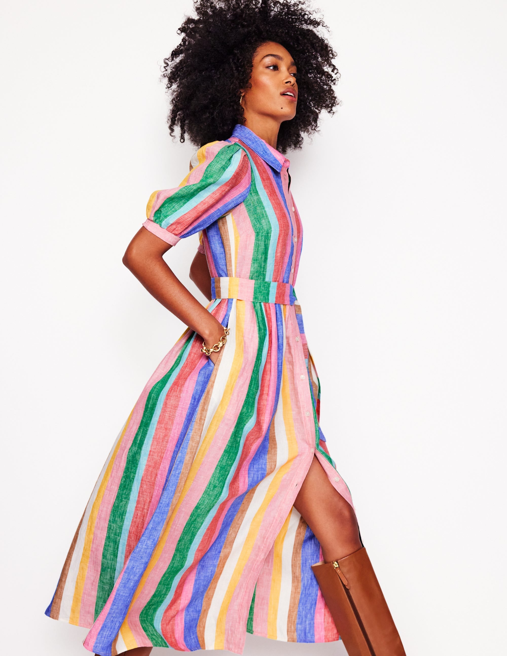 A woman wearing a colorful rainbow stripe maxi shirt dress with puffed sleeves and side pockets.
