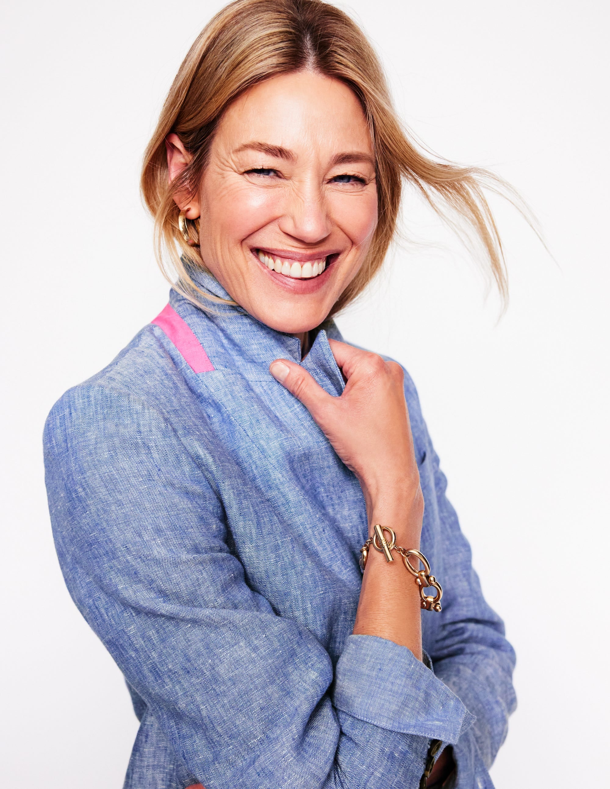 A woman wearing a blue chambray linen blazer with a revere collar and contrast piping.