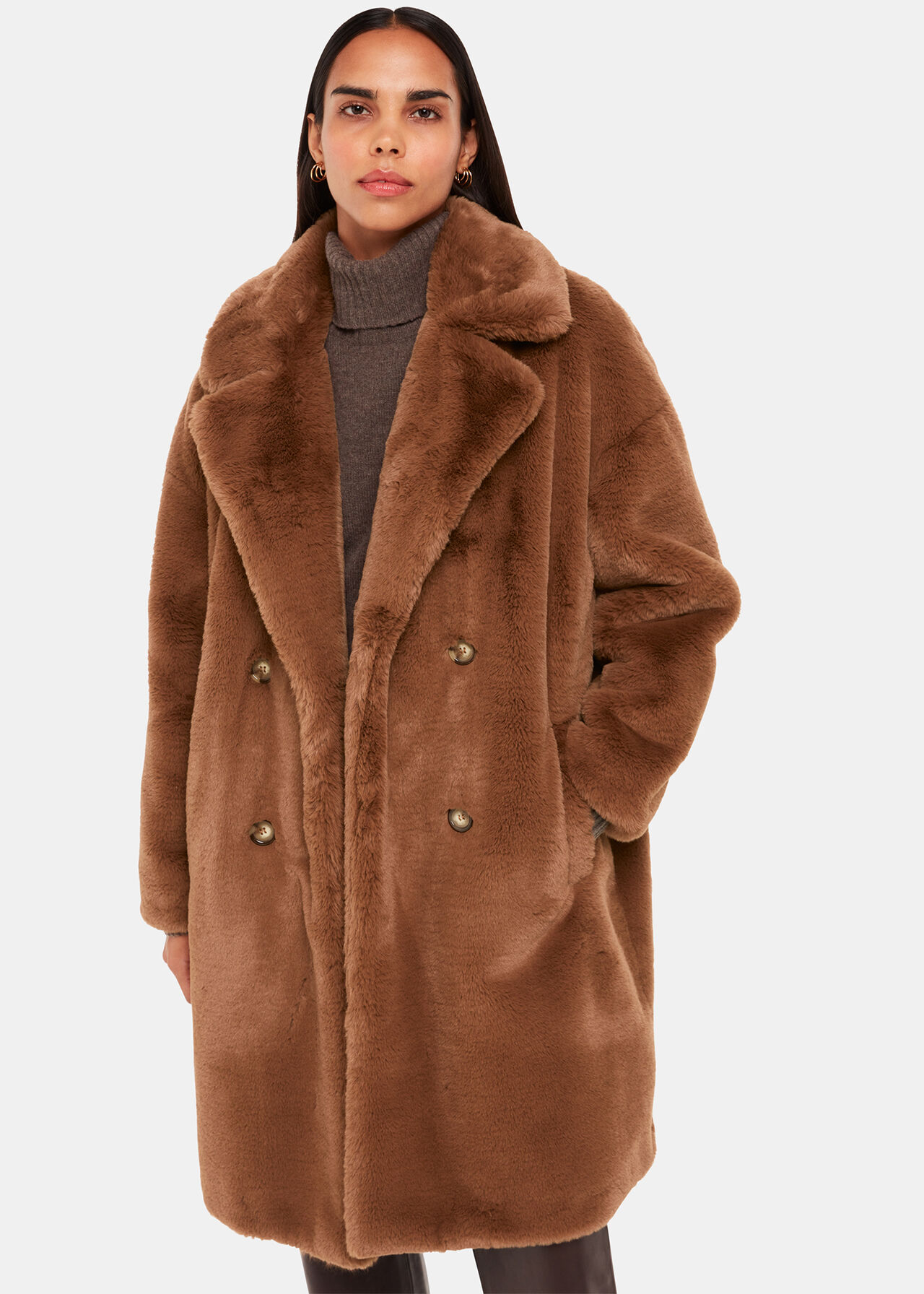 A woman wearing a large, brown faux fur coat with a wide collar and gold buttons, over a grey turtleneck.