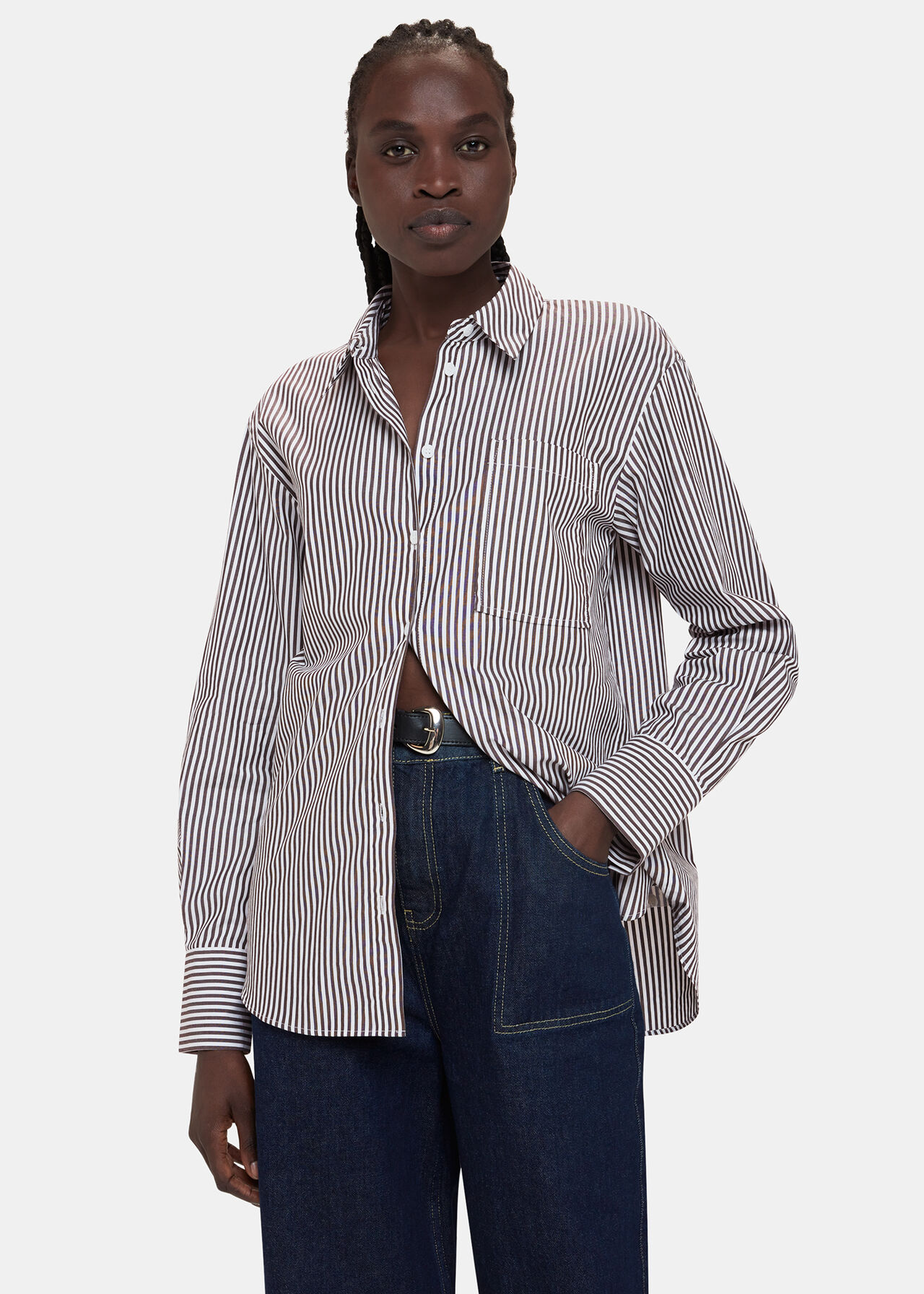 A woman wearing a black and white striped oversized shirt with a collar, buttoned front, and chest pocket.
