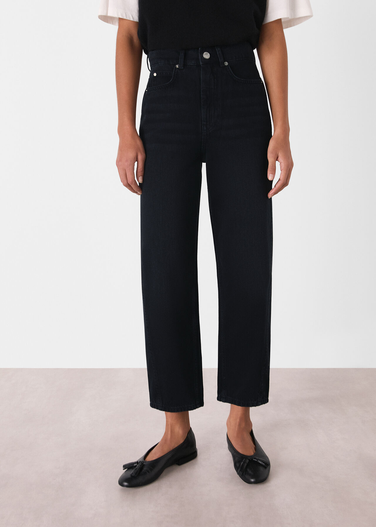 A pair of black women's high-waisted barrel-leg jeans with a loose fit, shown on a model.