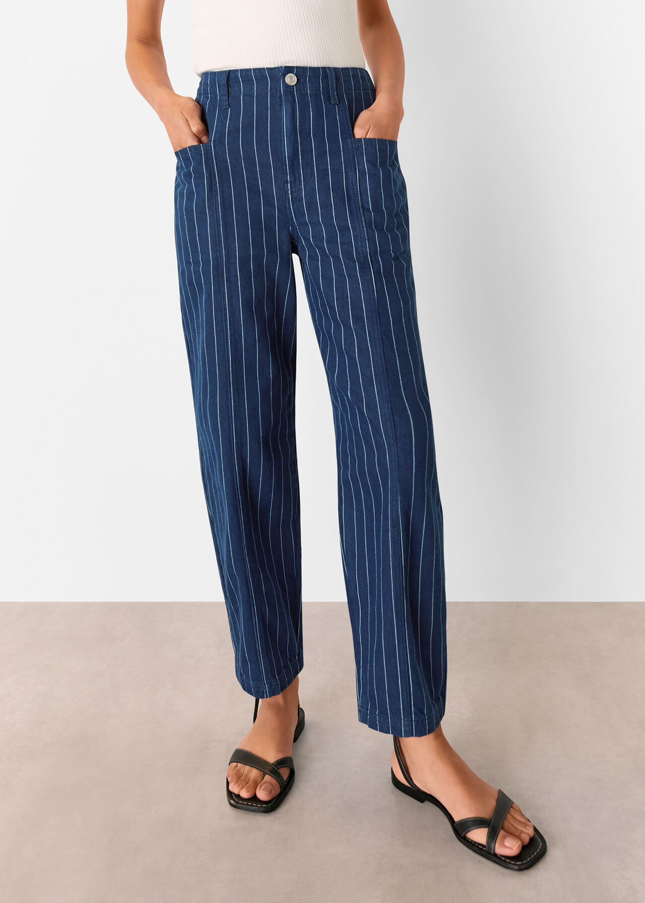 A pair of women's navy pinstripe barrel leg jeans with pockets, belt loops, and a carrot silhouette.