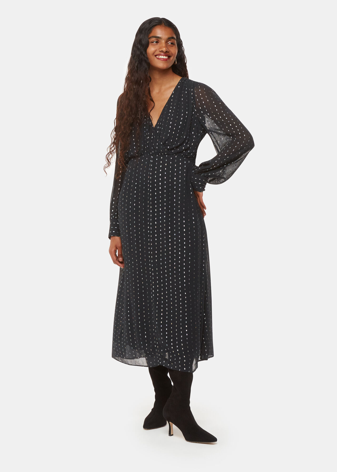 A woman wearing a black midi dress with metallic stripes, featuring a V-neckline and semi-sheer sleeves.