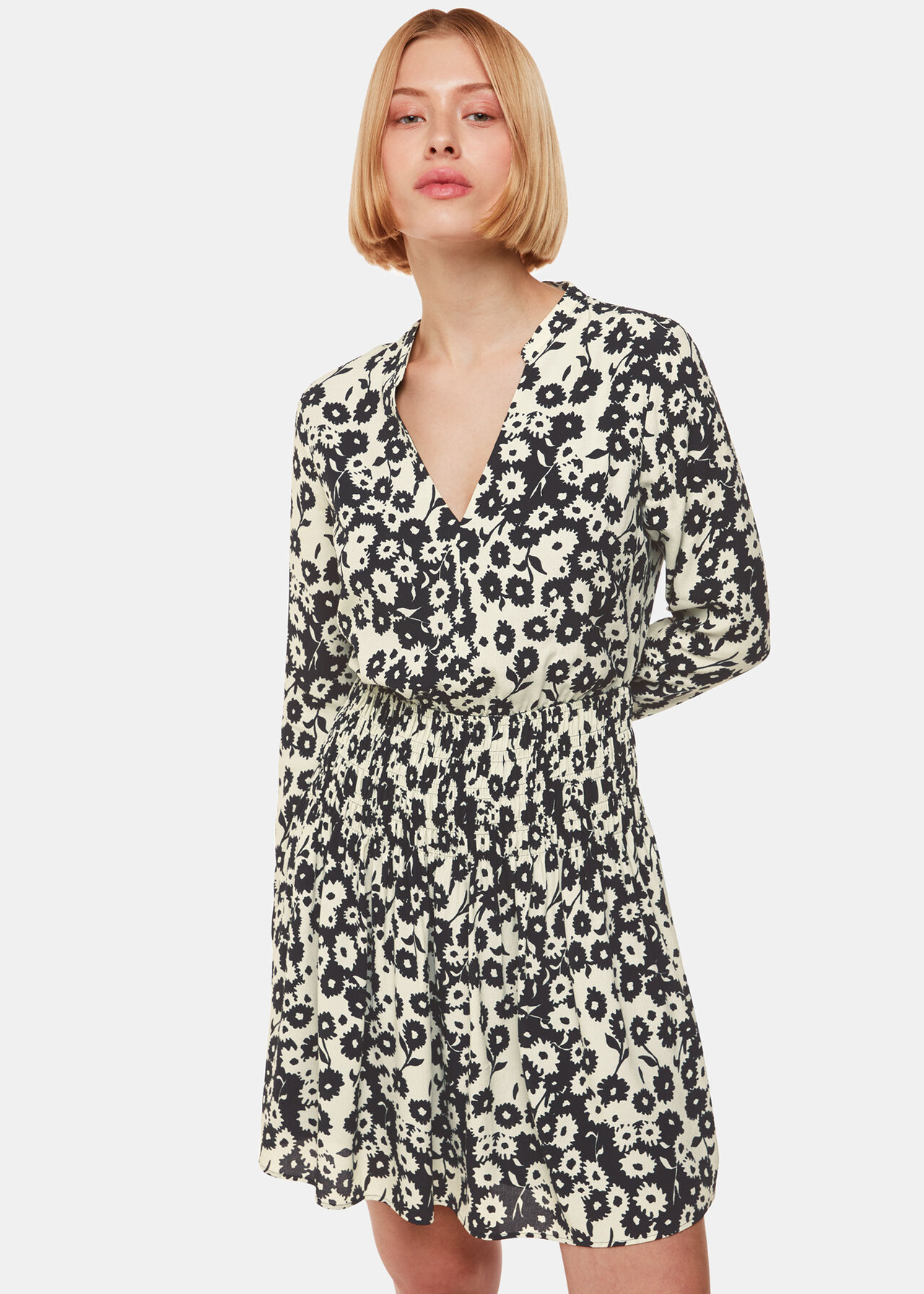 A woman wearing a black and white floral dress with a V-neck and ruched waist.