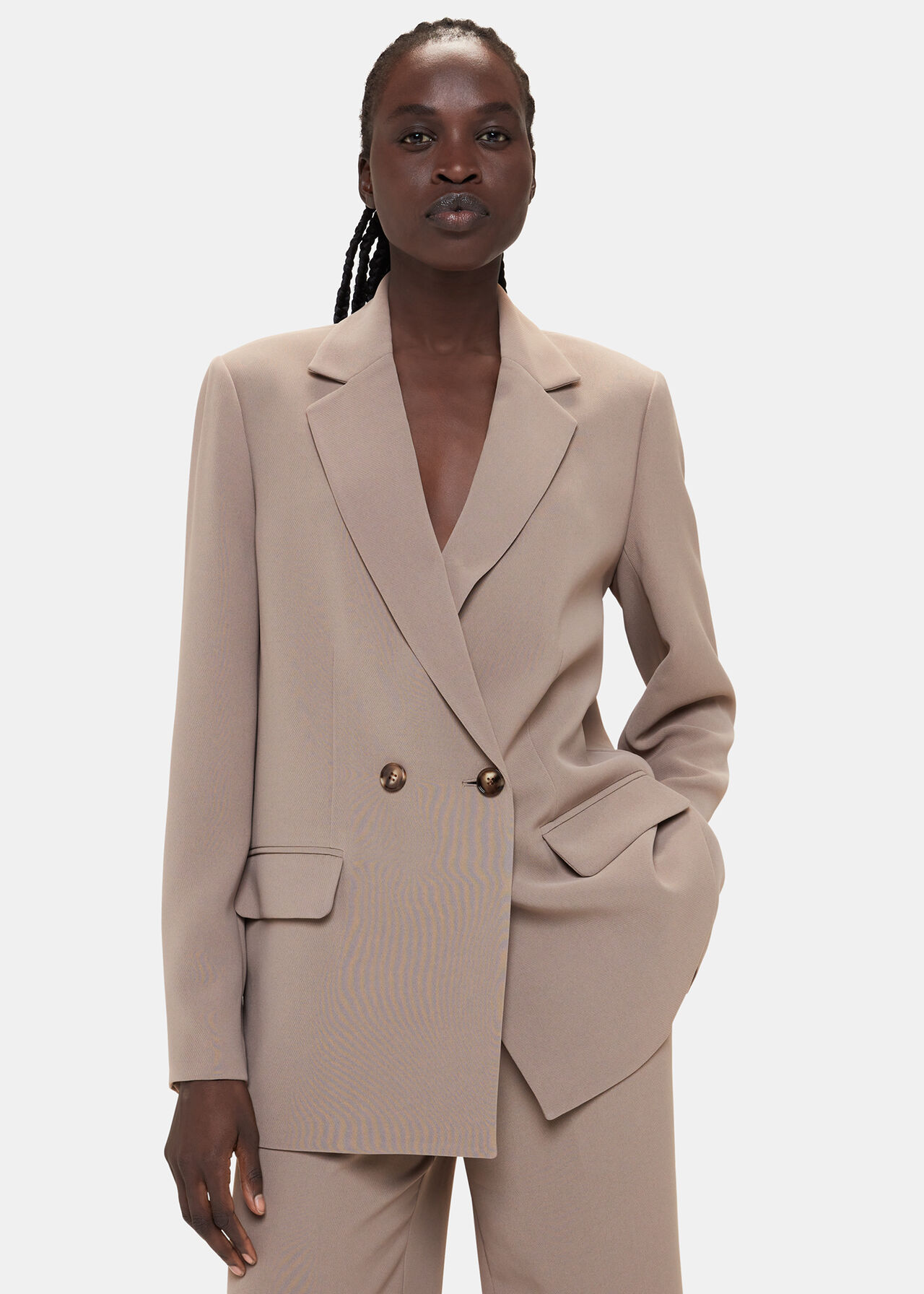 A woman wearing a taupe double-breasted blazer with a relaxed fit, collar detail, and centre front buttons.