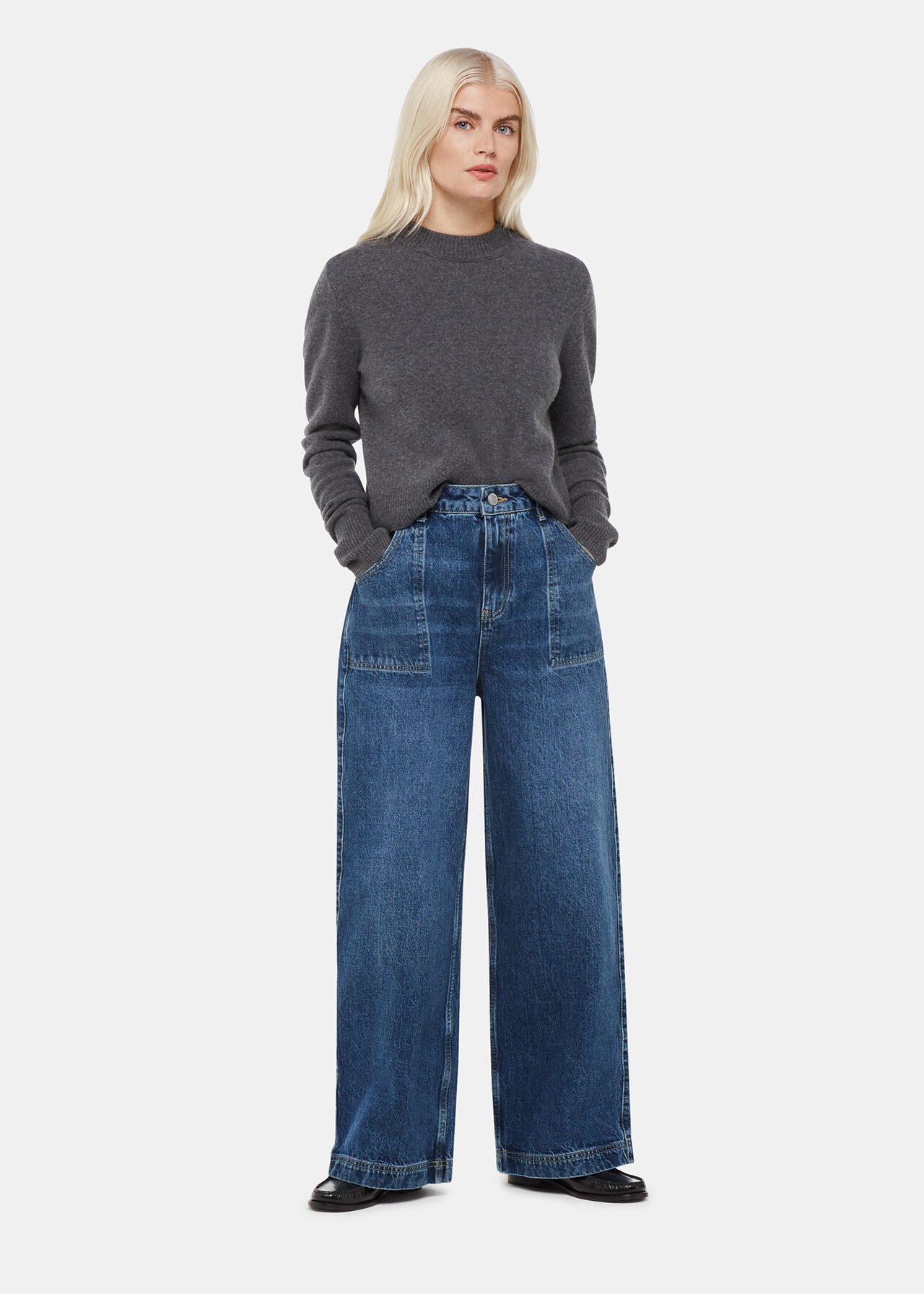 A woman wearing mid wash denim straight-leg jeans with a high waist, paired with a grey sweater.