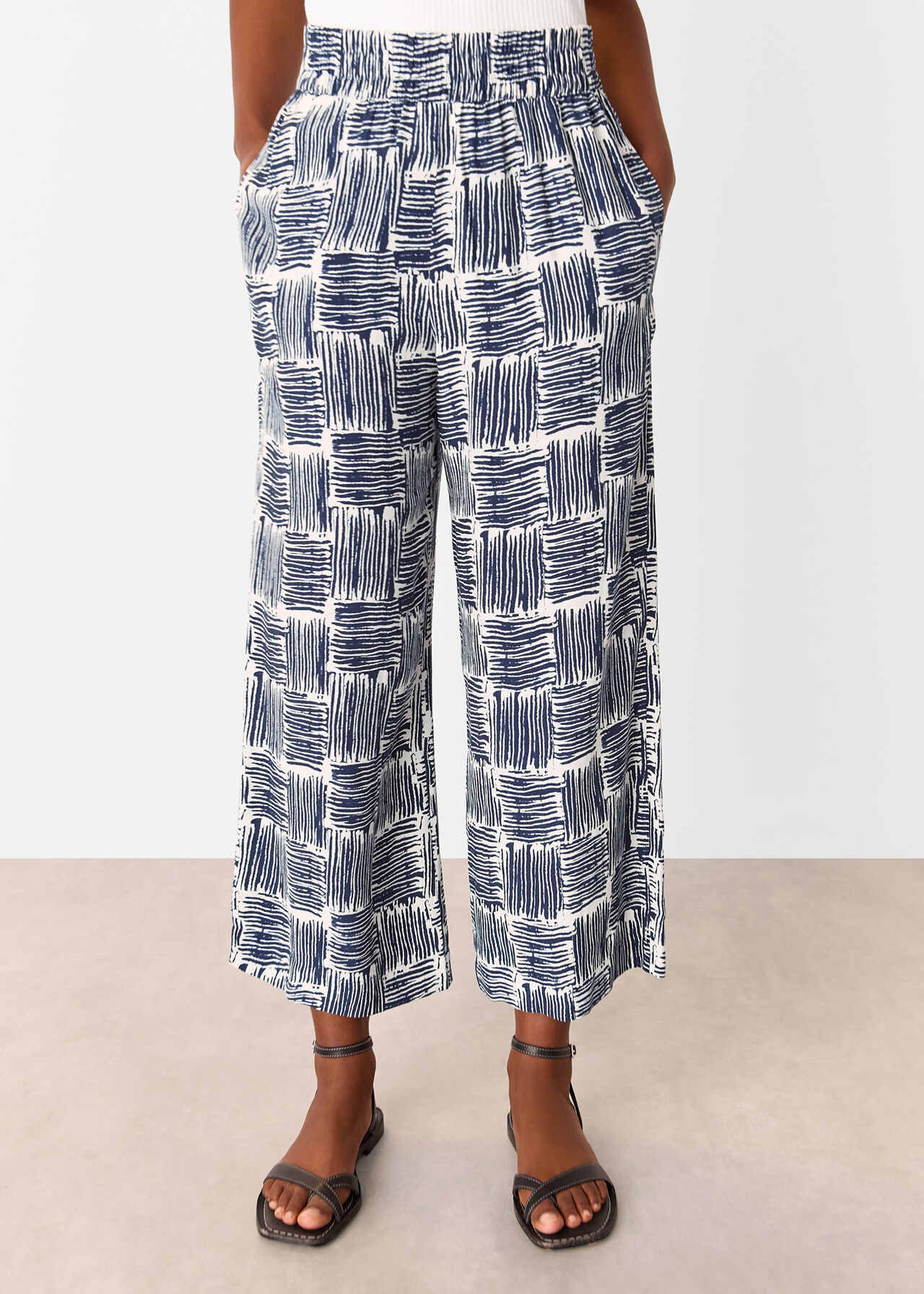 A pair of navy hatch squares cropped trousers with a relaxed fit and straight legs, shown on a person with hands in pockets.