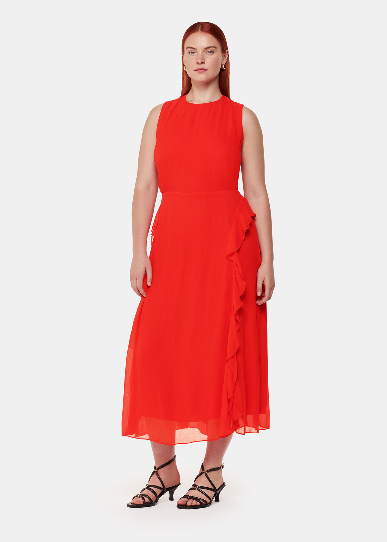 A woman wearing a red sleeveless midi dress with frill details and side splits, paired with black strappy heels.