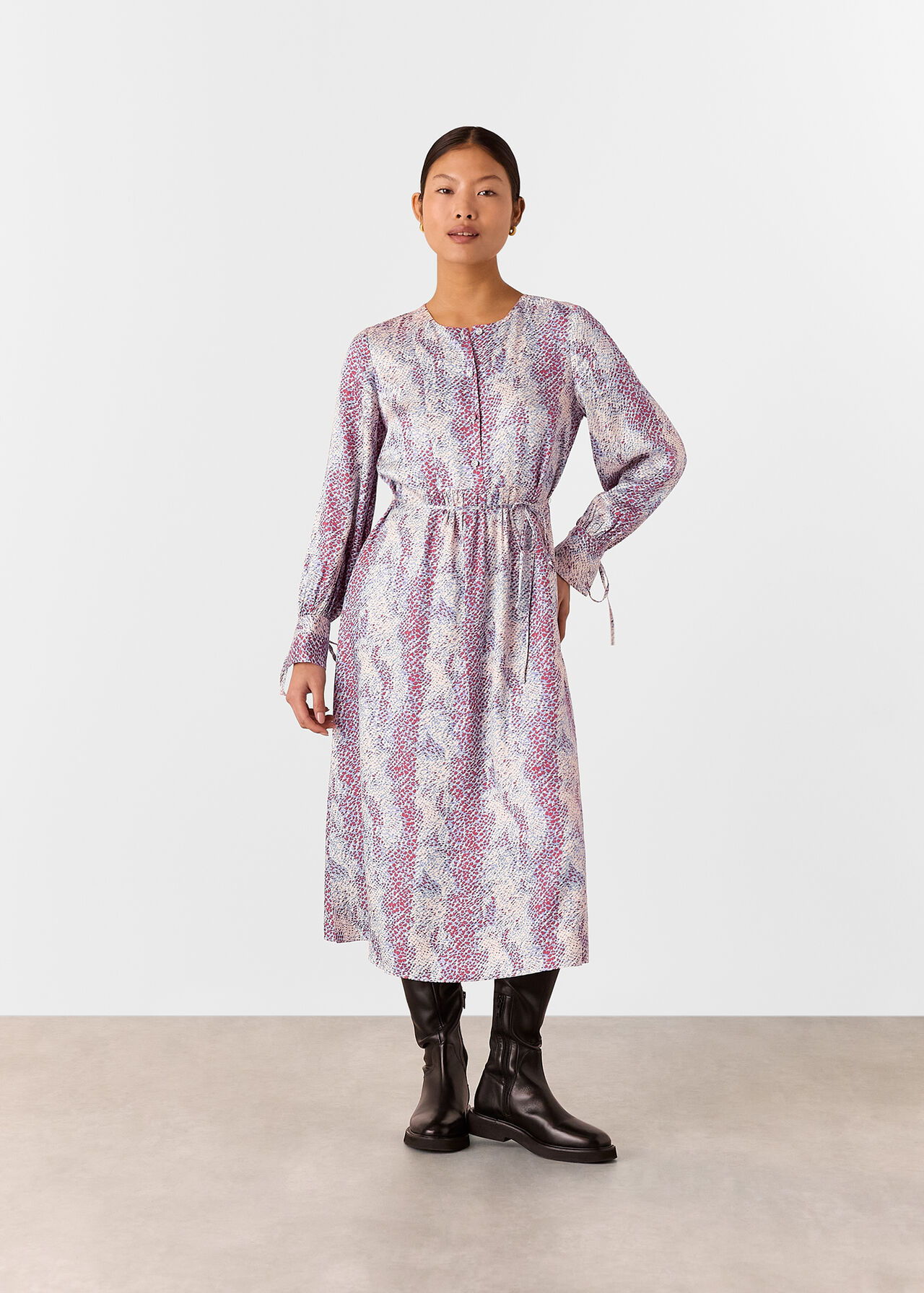 A woman wearing a midi dress with a multi-coloured snake print, long sleeves, and a pleated skirt.