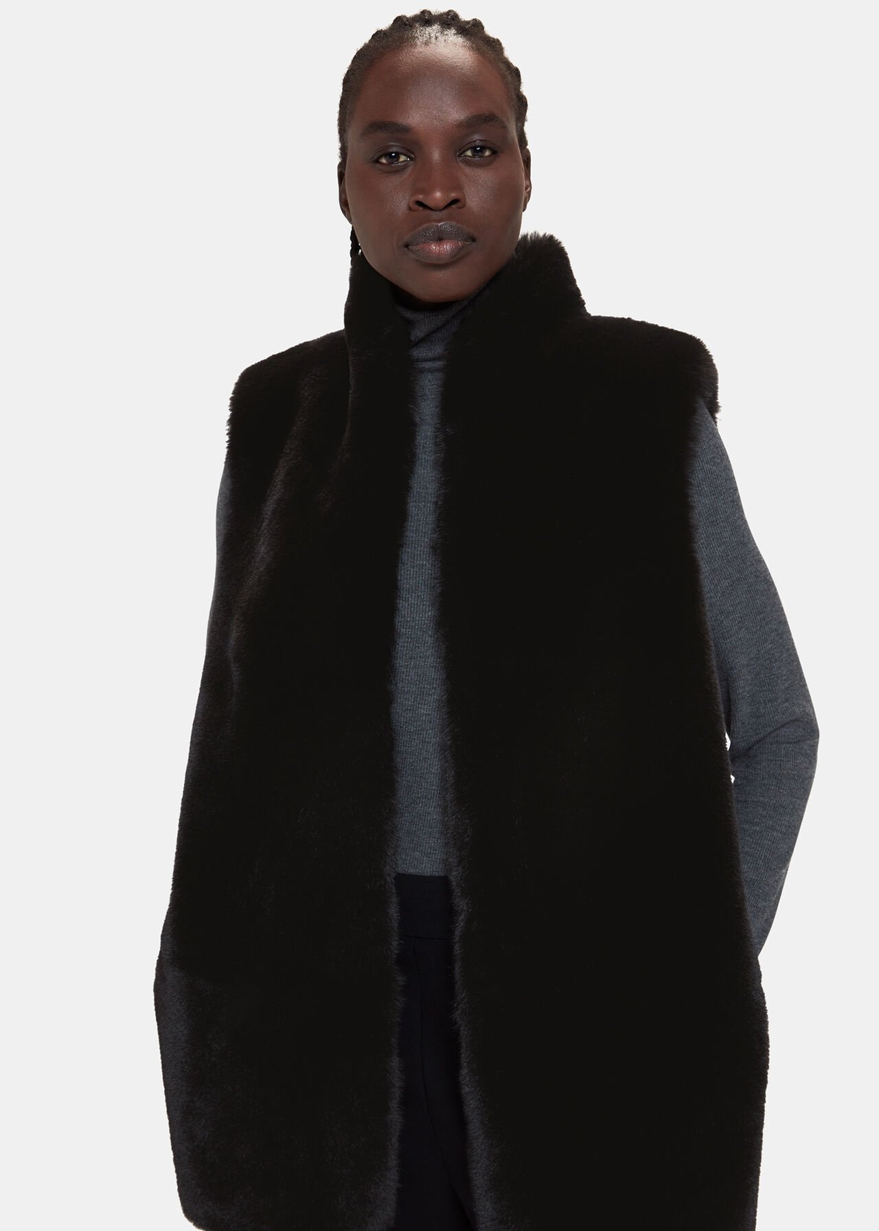 A woman wearing a black faux fur gilet with a high neck collar, sleeveless design, and relaxed fit.
