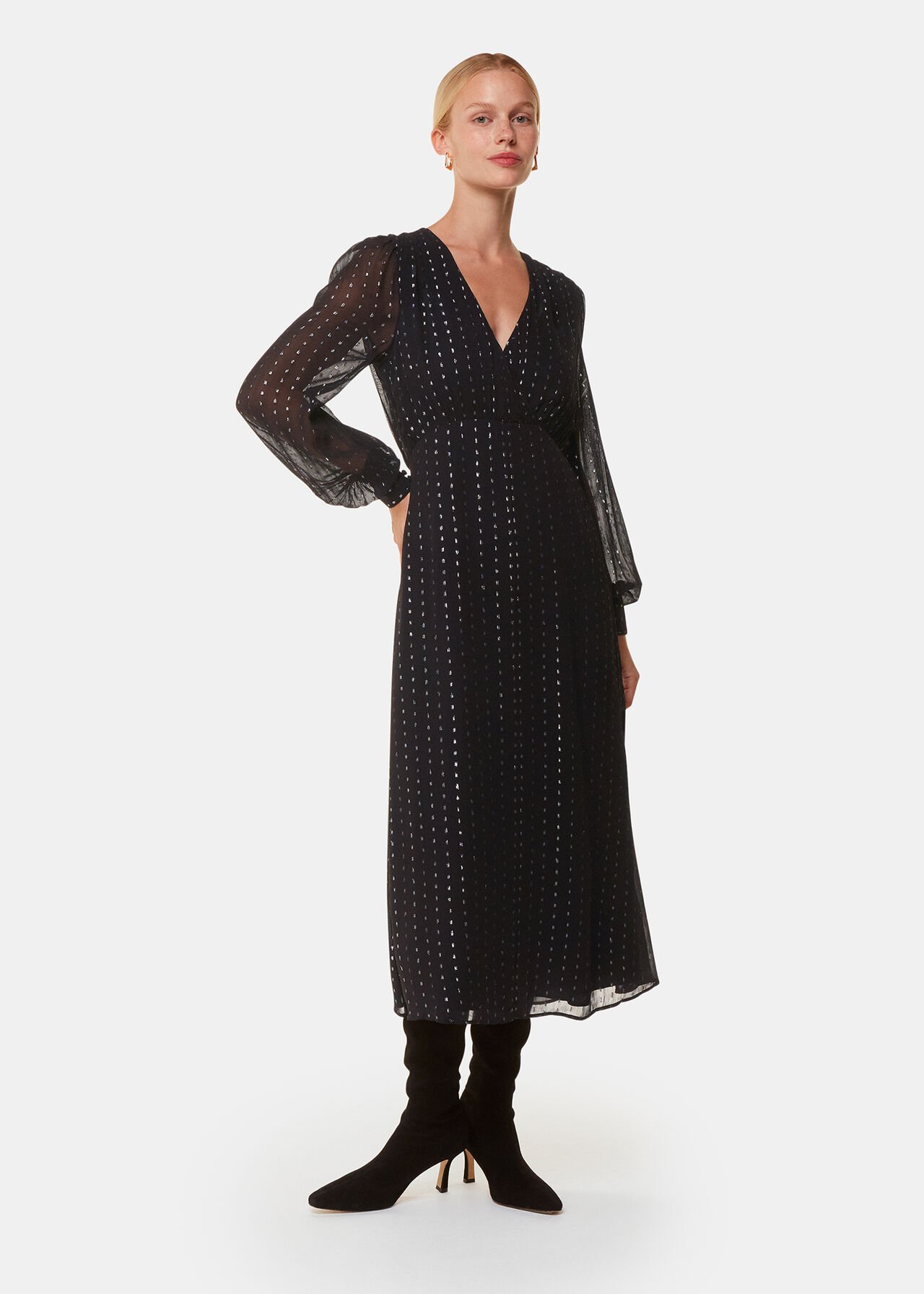 A woman wearing a black midi dress with metallic stripes, V-neckline, and semi-sheer long sleeves.
