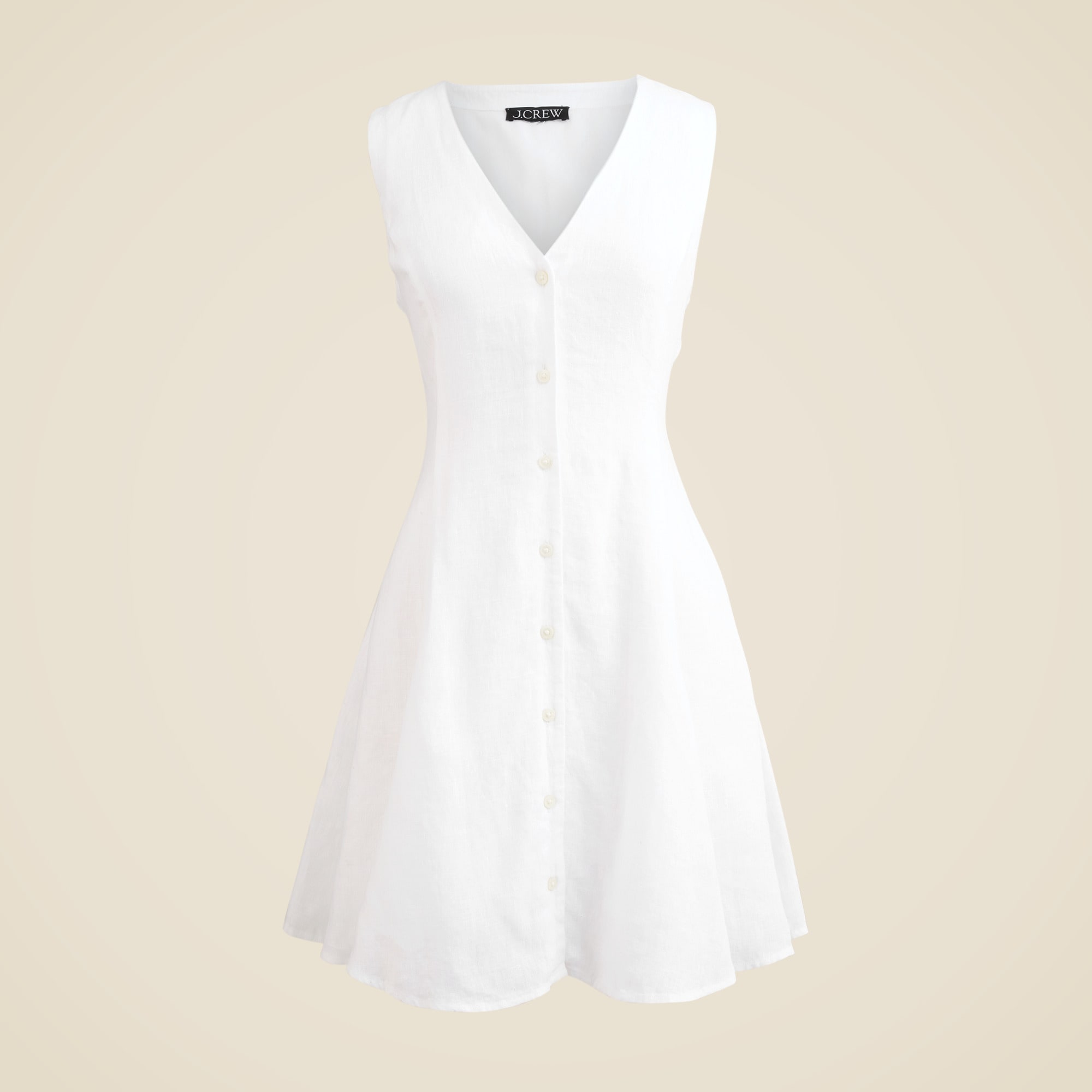 A white linen mini dress with a V neckline, button-down front, and back tie detail, displayed on a plain background.