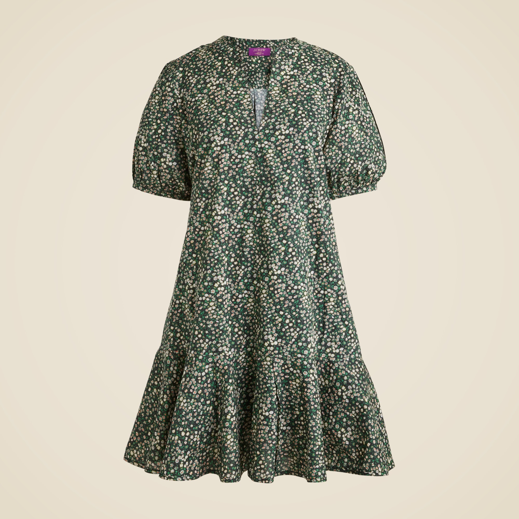A women's dress with a floral Liberty&reg; Marguerite print, green background, short puff sleeves, split neckline, and ruffle hem.