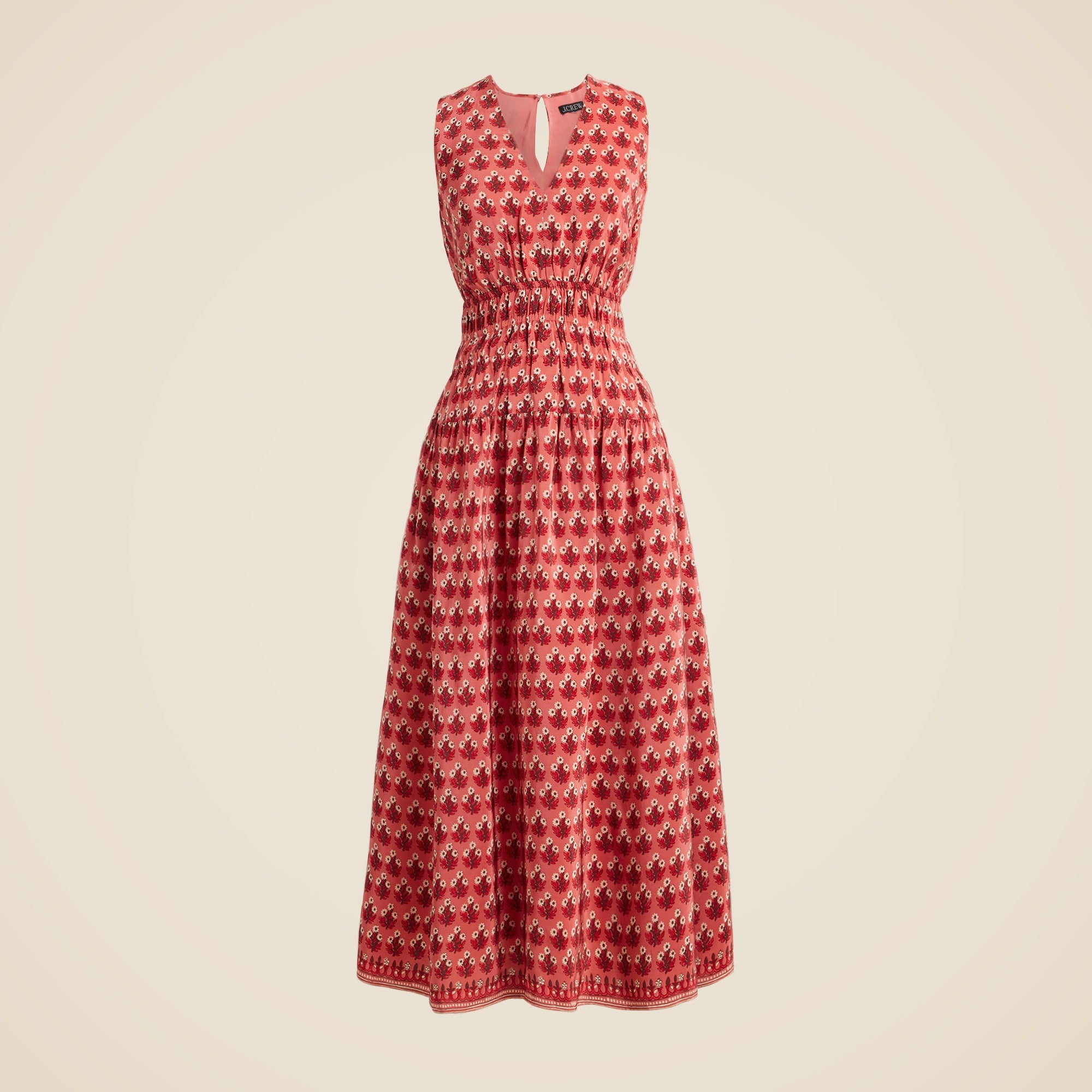 A sleeveless pink dress with a floral block print, smocked bodice, and pockets.