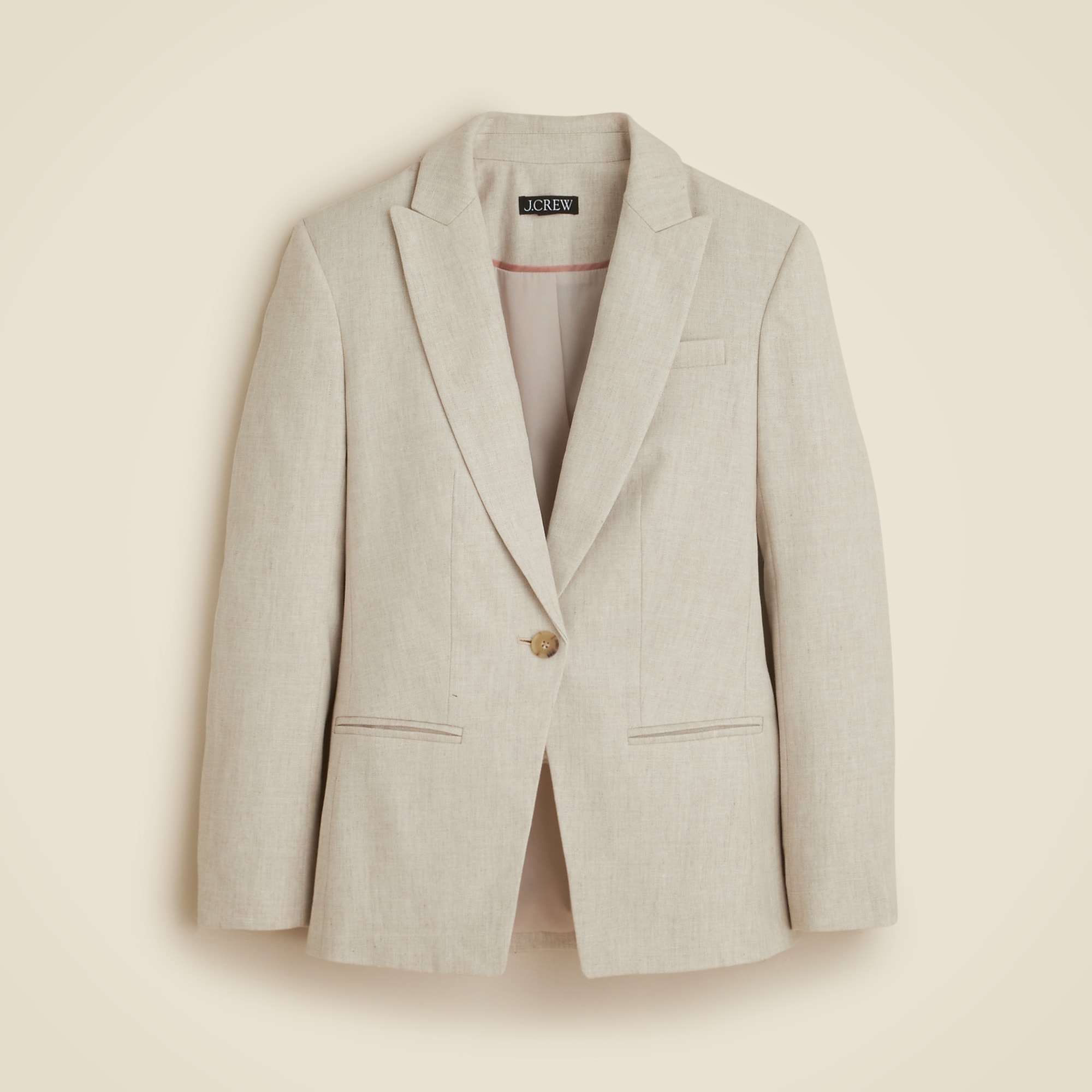A beige women's blazer with braided trim details on the lapel, single-breasted, peak lapel, welt pockets, long sleeves, and a longer length.