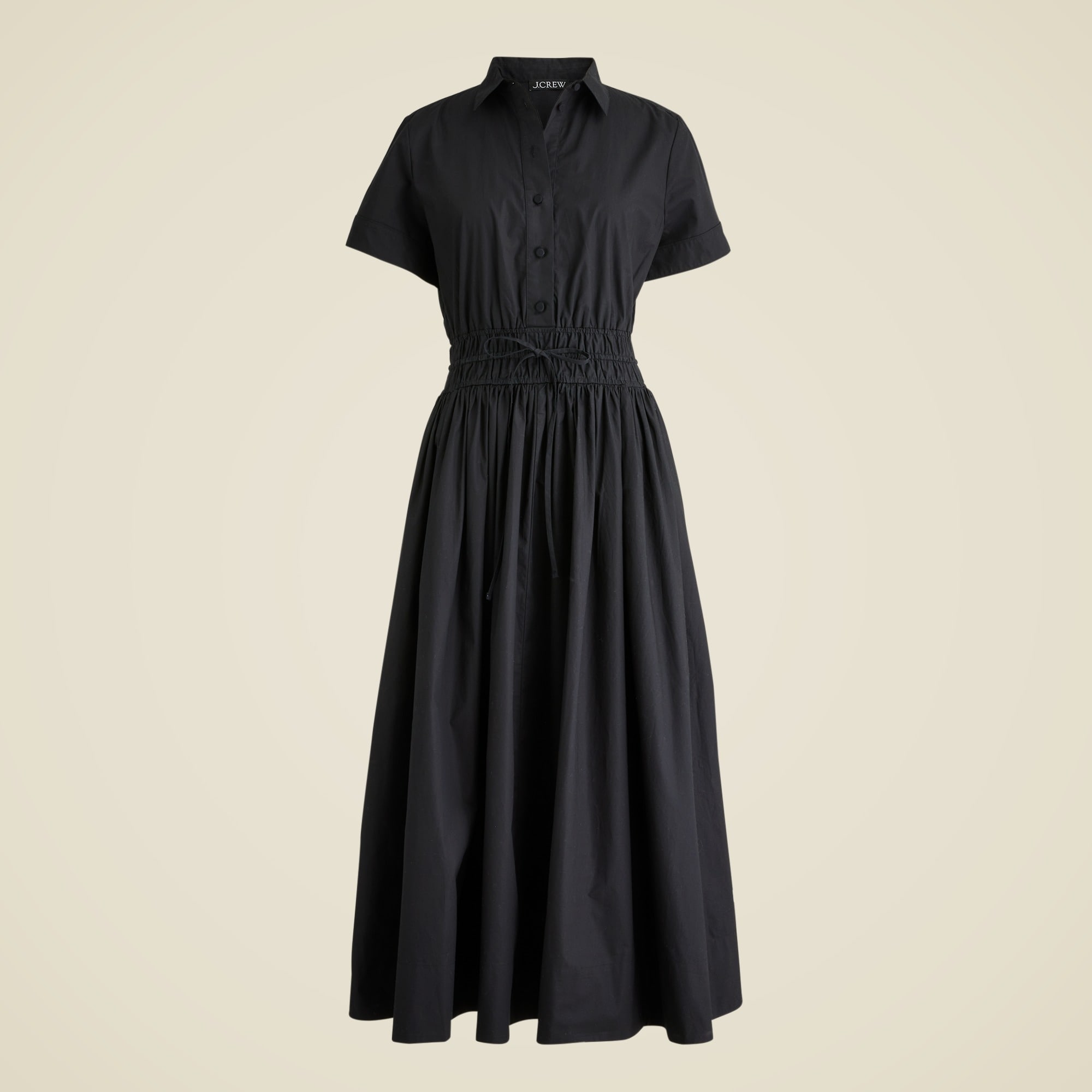 A women's white cotton poplin shirtdress with buttons halfway up the front, short sleeves, and a smocked waist with a tie.