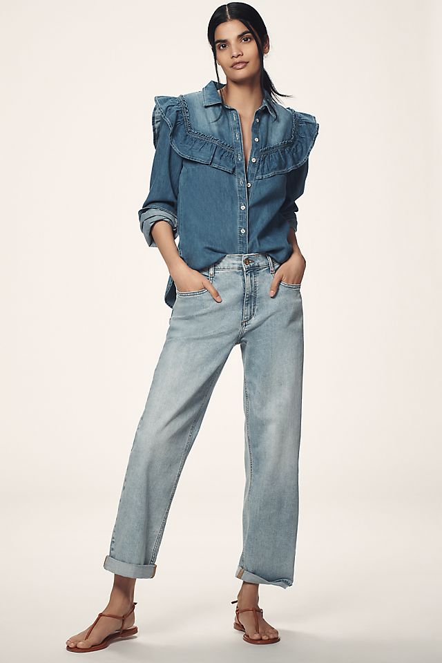 A woman wearing light blue high-rise relaxed jeans with a baggy fit, paired with a denim shirt and sandals.