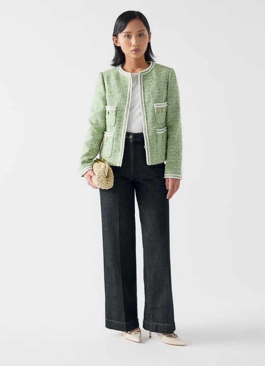 A pair of black wide-leg denim trousers with button details and contrast stitching, worn by a woman in the image.