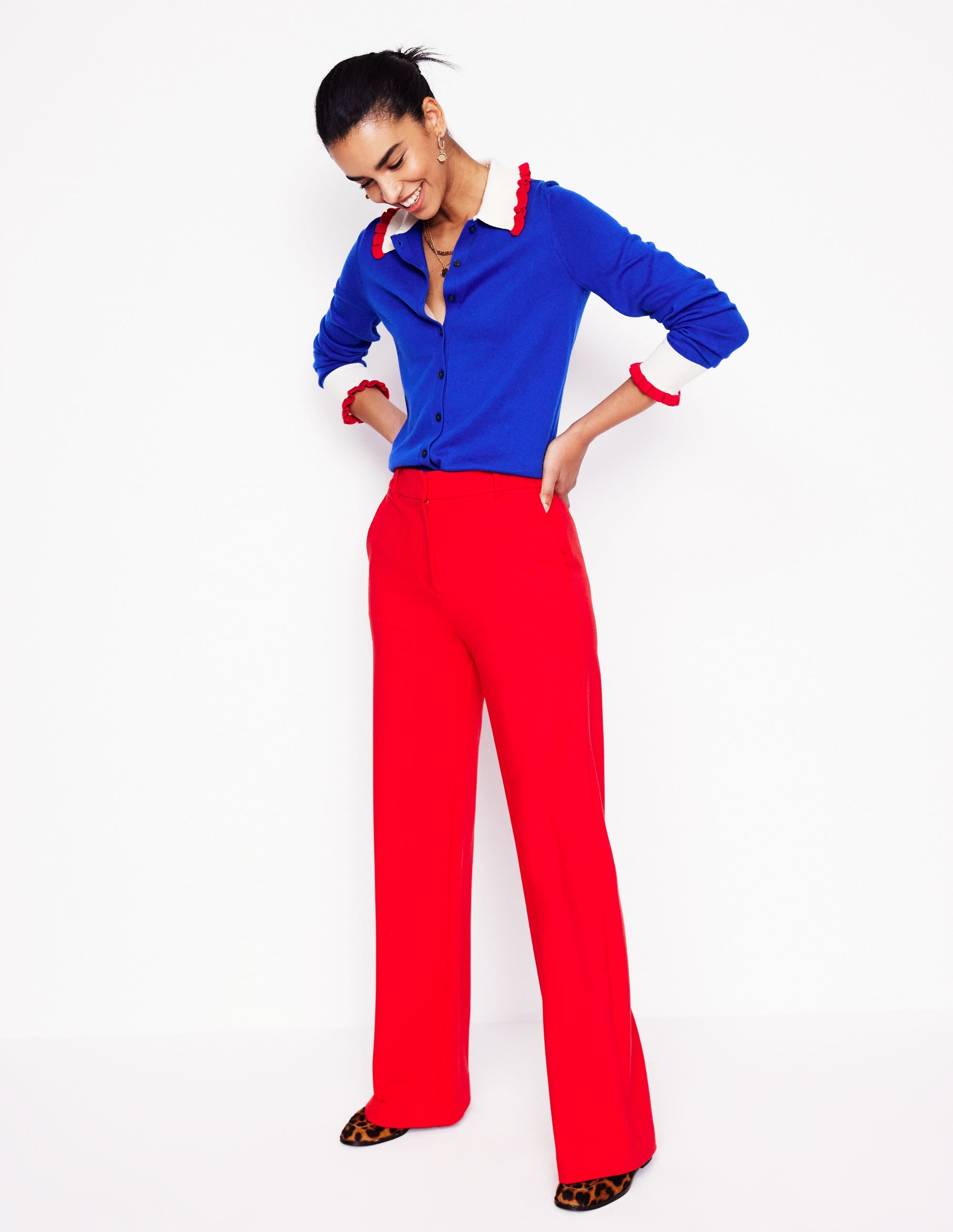 A woman wearing bright red, full-length, straight-leg ponte trousers with front creases.