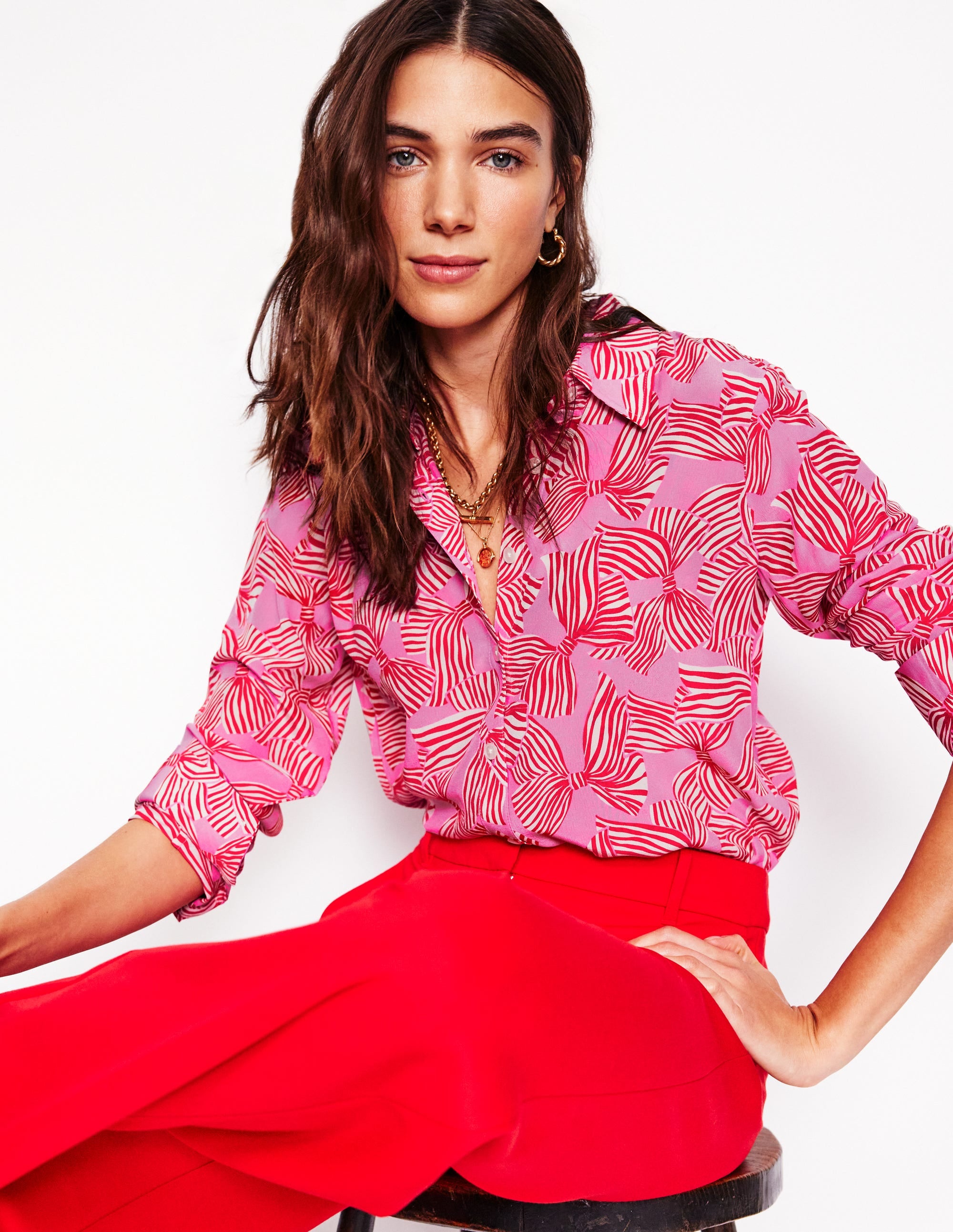 A woman wearing a lavender silk shirt with a scattered bow print, long sleeves, and a classic collar.