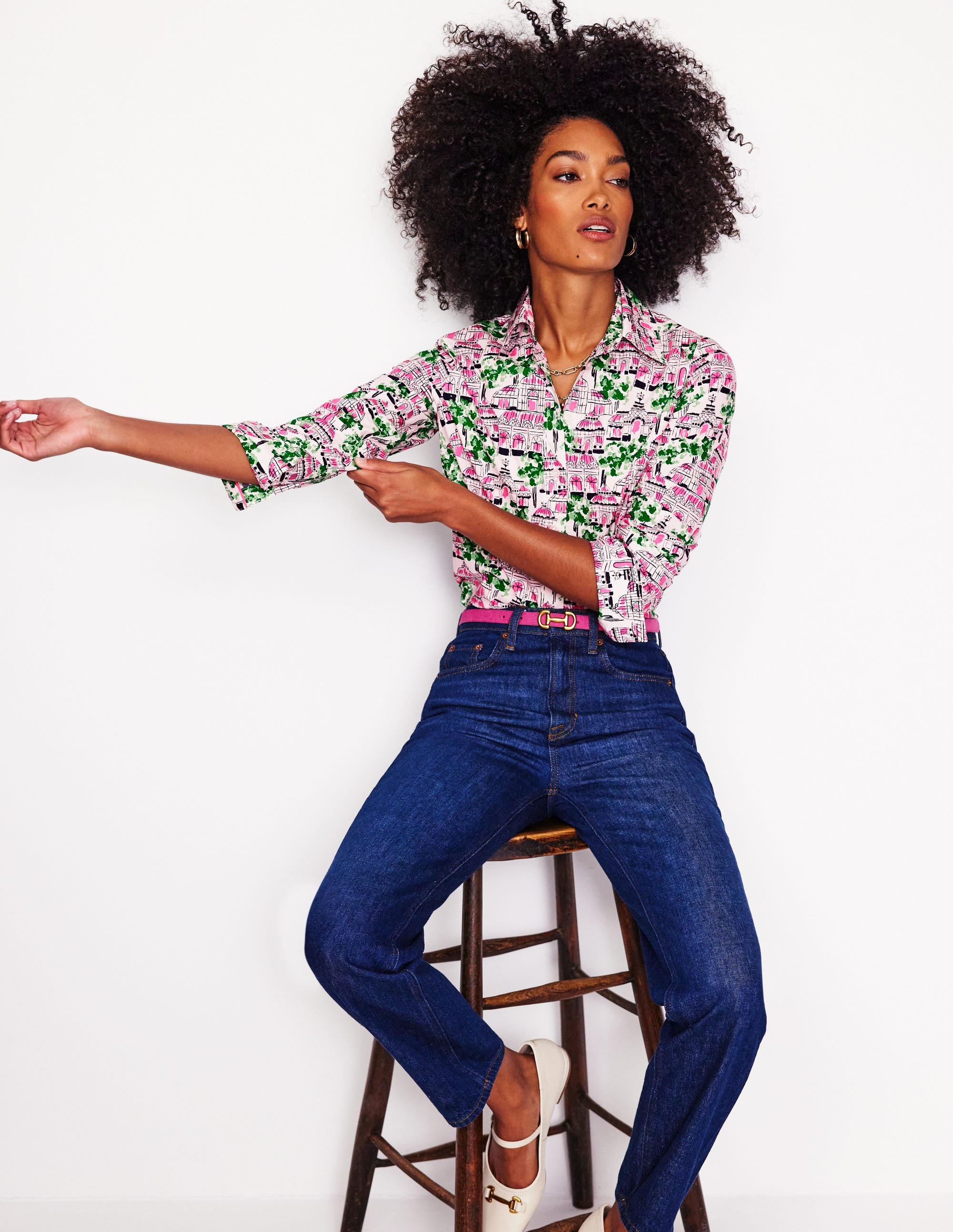 A woman wearing a women's cotton shirt with a botanical greenhouse print in ivory, pink, green, and black, featuring a classic collar and button-down front.
