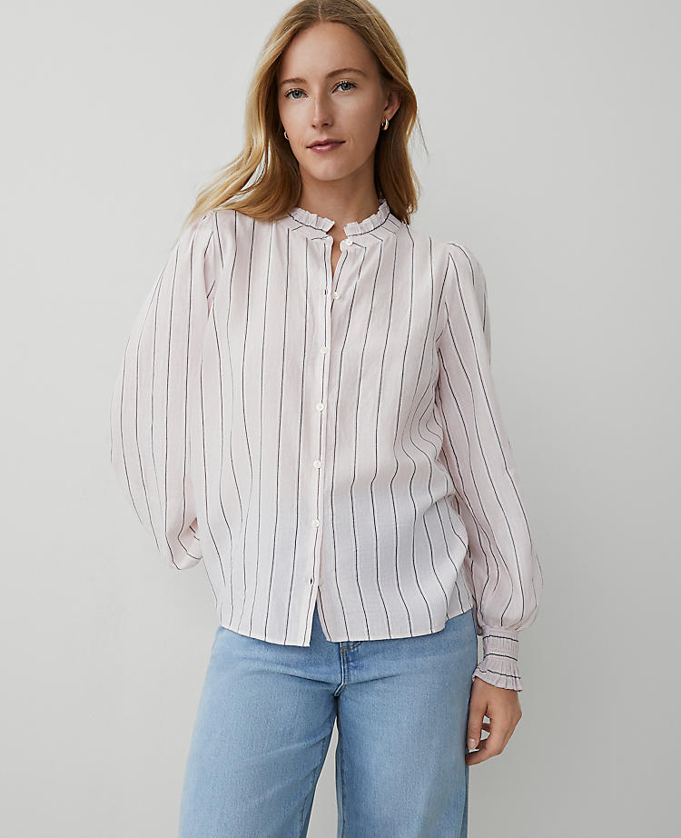 A woman wearing a petite striped blouse with a standing collar, long puffed sleeves, and a shirttail hem, featuring vertical stripes and a cutout detail at the collar.