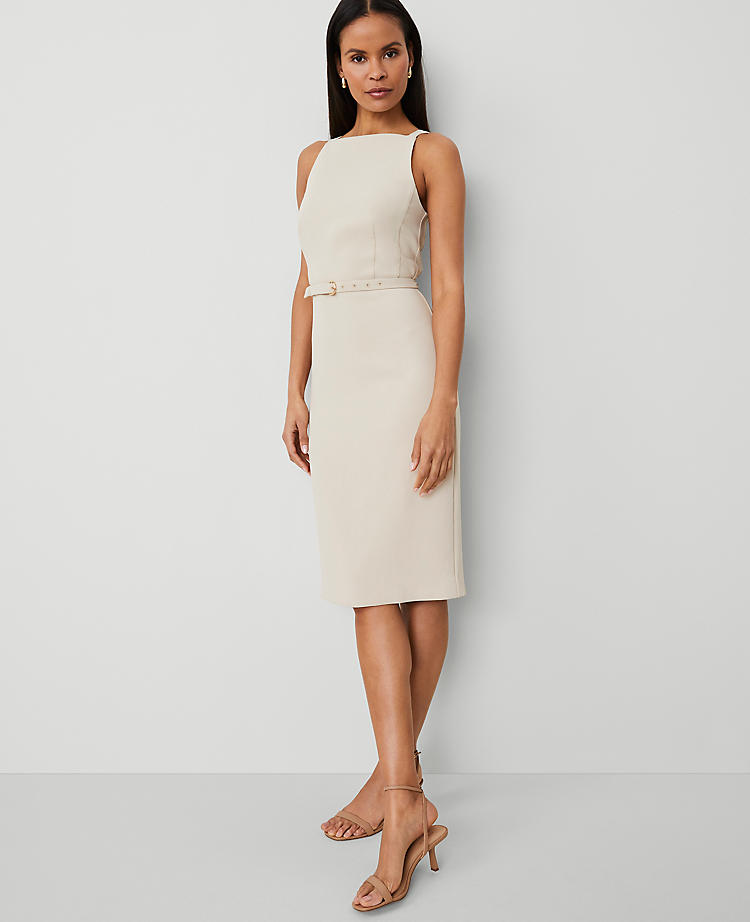 A woman wearing a cream-colored petite sheath dress with spaghetti straps, a square neckline, and a belted waist, paired with nude high-heeled sandals.