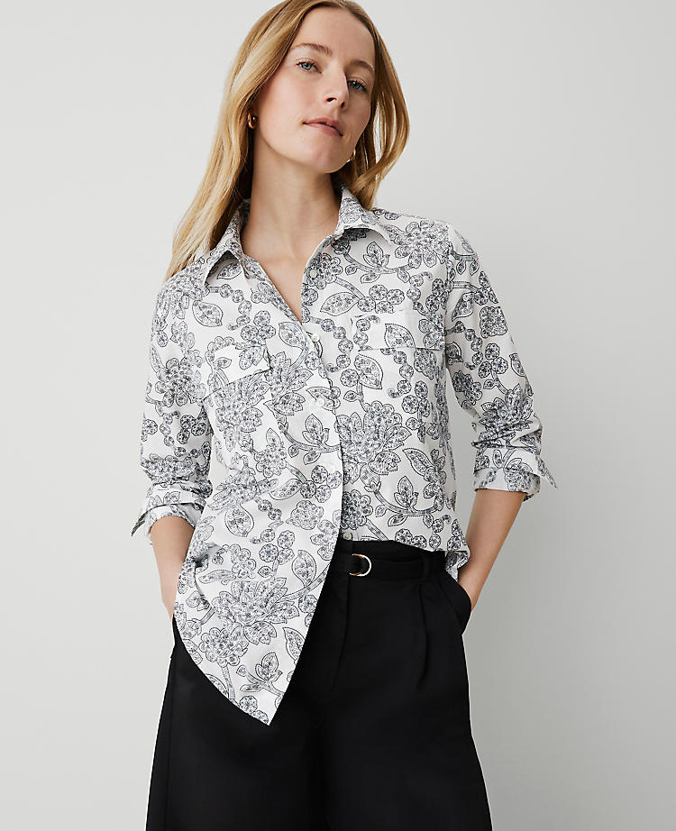 A woman wearing a white blouse with navy paisley print, long sleeves with button cuffs, and a shirttail hem.